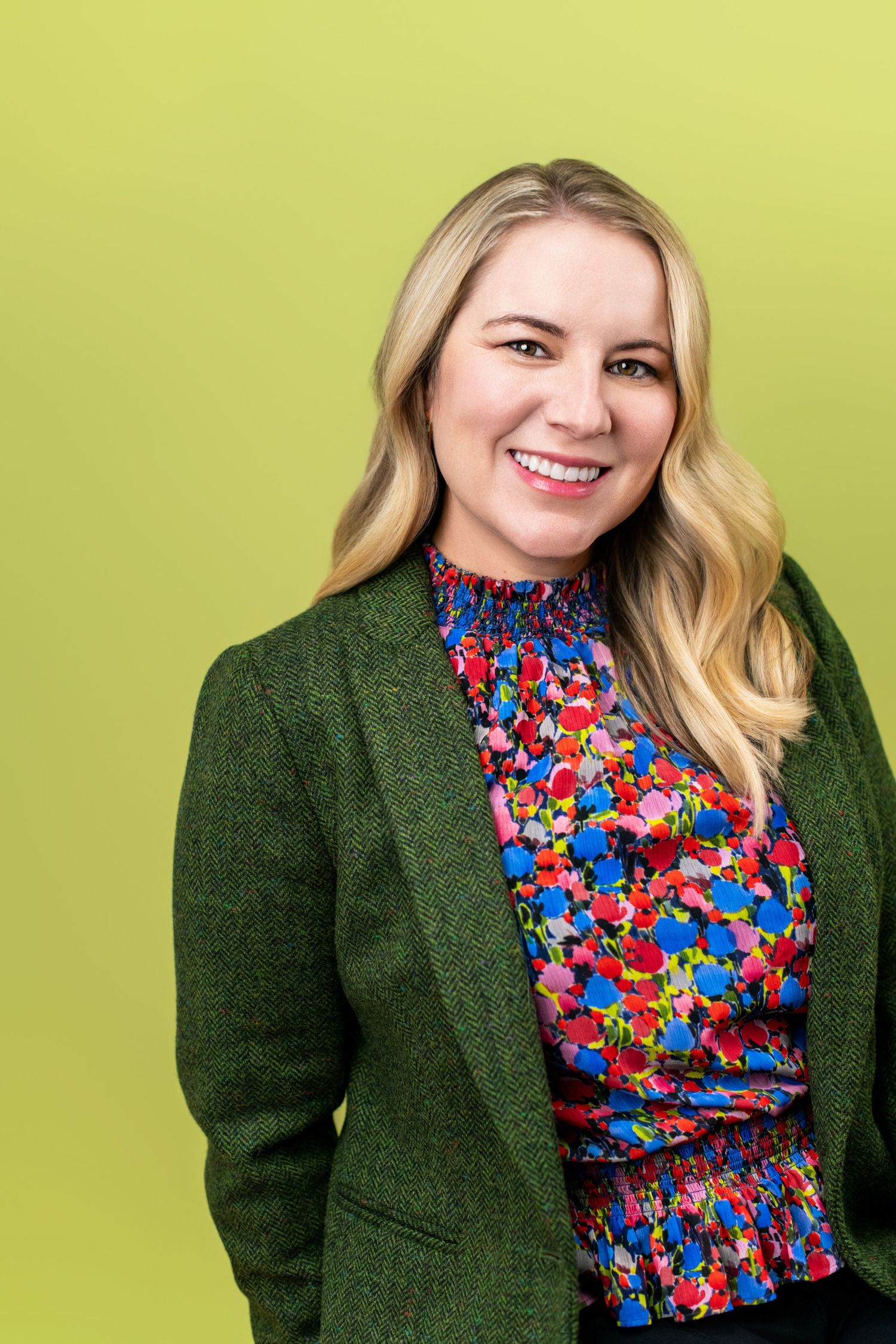 Business professional headshot of a smiling woman against a green studio background, photographed at Nice Headshots in Los Angeles