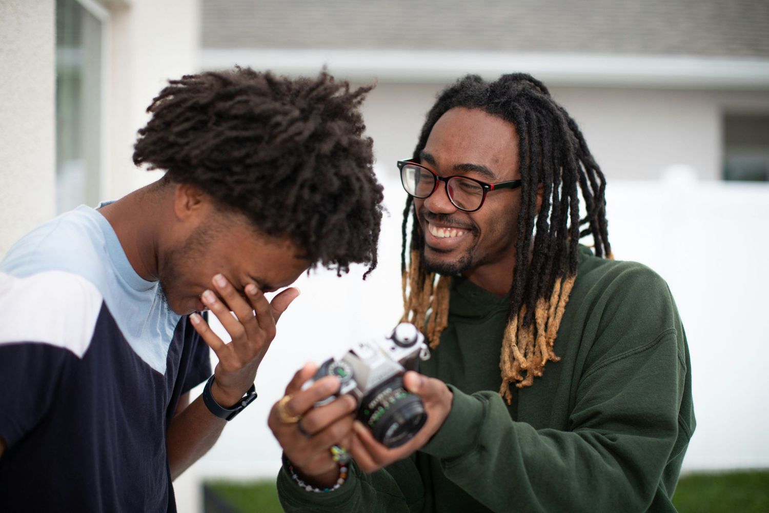 Two friends reviewing photos on a camera, representing a DIY headshot setup that lacks professional quality and direction.