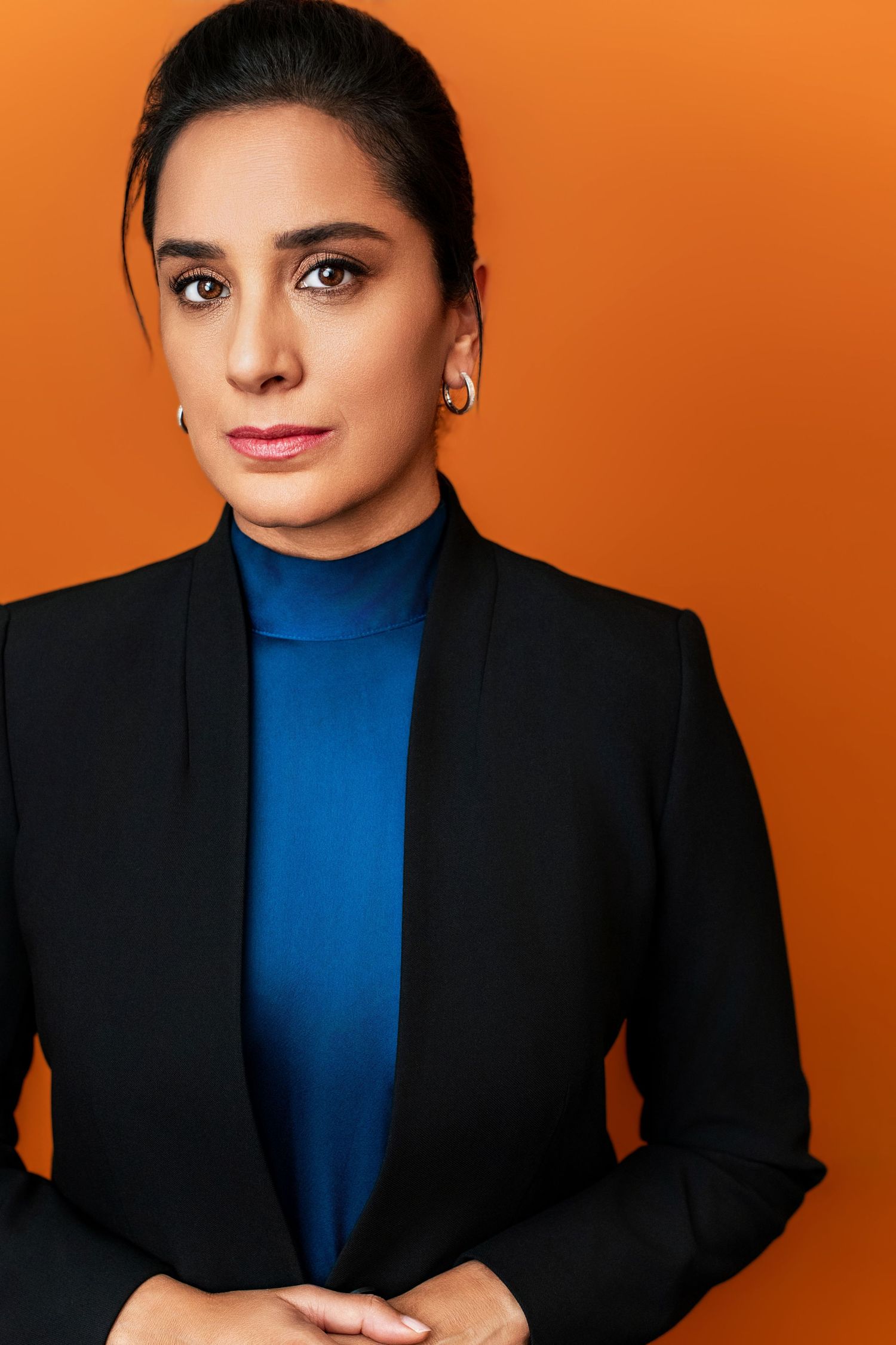 Confident actor headshot of a woman on an orange background, photographed in a Los Angeles studio