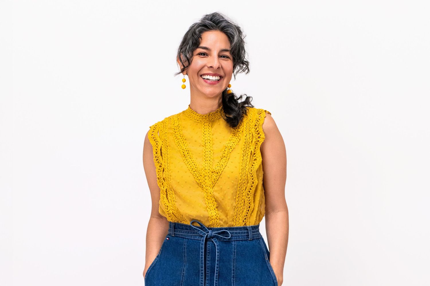 Approachable professional woman wearing a yellow blouse on a white background for a relaxed lifestyle headshot.