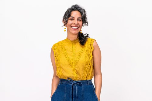 Approachable professional woman wearing a yellow blouse on a white background for a relaxed lifestyle headshot.