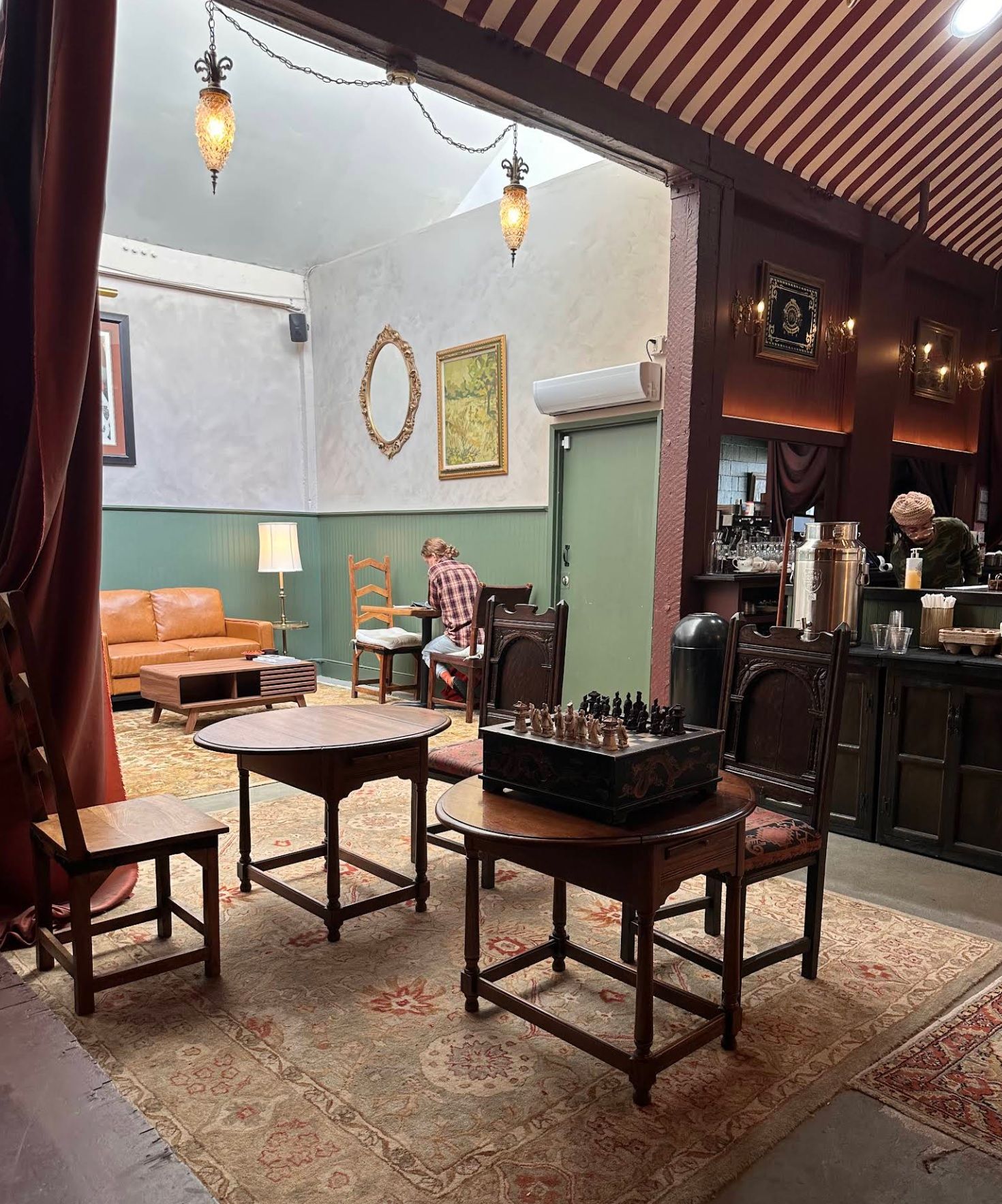Warm, cozy interior of Kissaten Corazon with a guest reading and a chess board set up on a wooden table.
