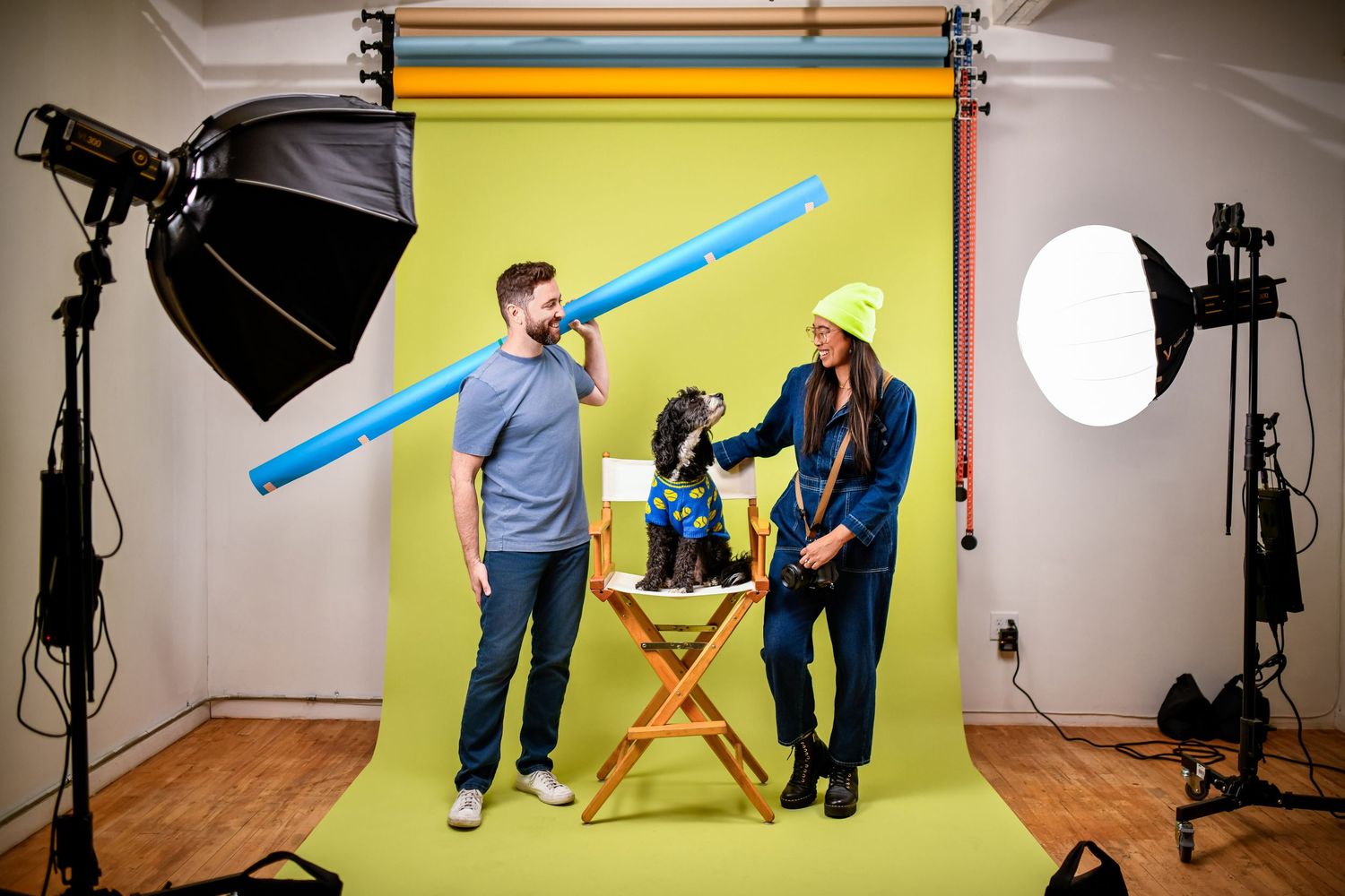 Nice Headshots team interacting in their Los Angeles studio with colorful backdrop, lighting equipment, and their dog during a shoot