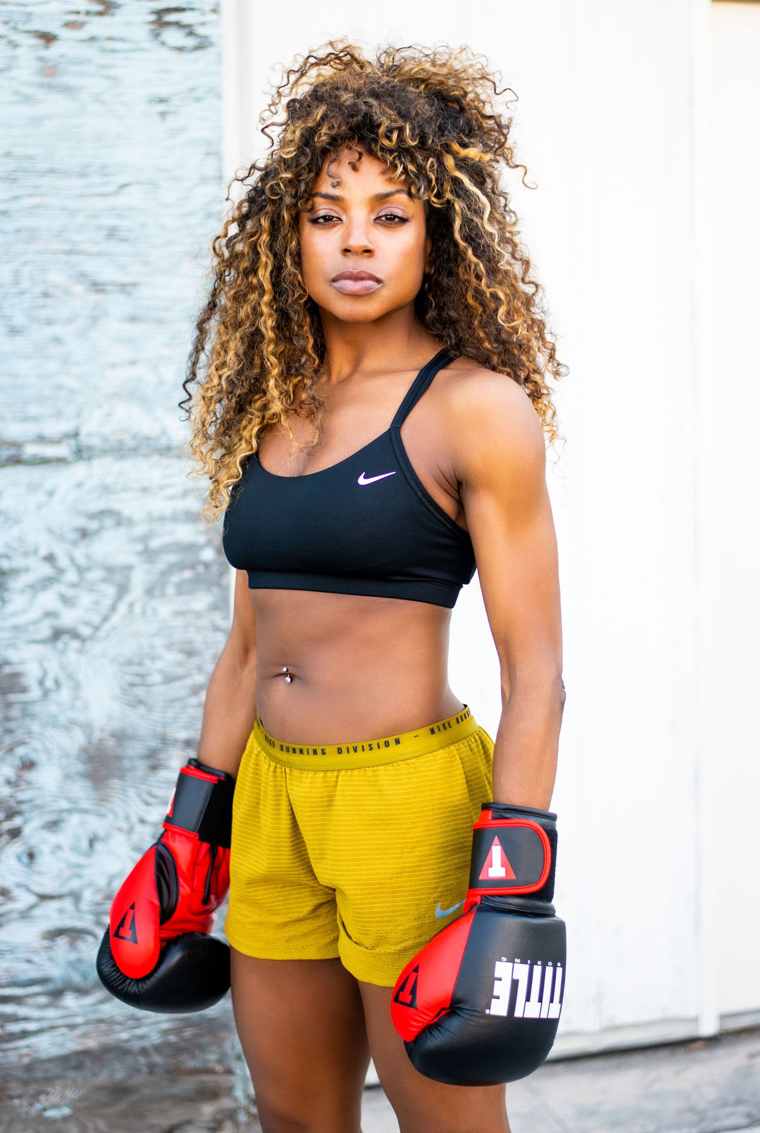 Fitness lifestyle headshot in Los Angeles featuring strong athletic woman wearing boxing gloves, confident outdoor portrait.