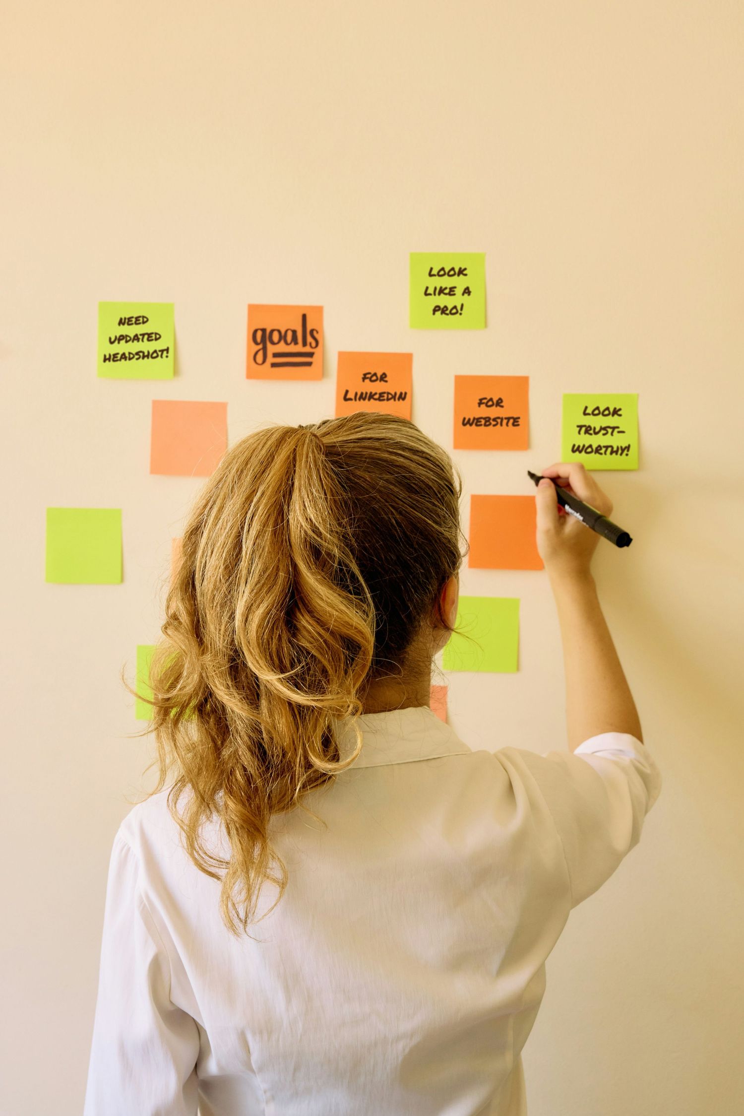 Person planning headshot goals with sticky notes for LinkedIn, website, and professional branding before choosing outfits