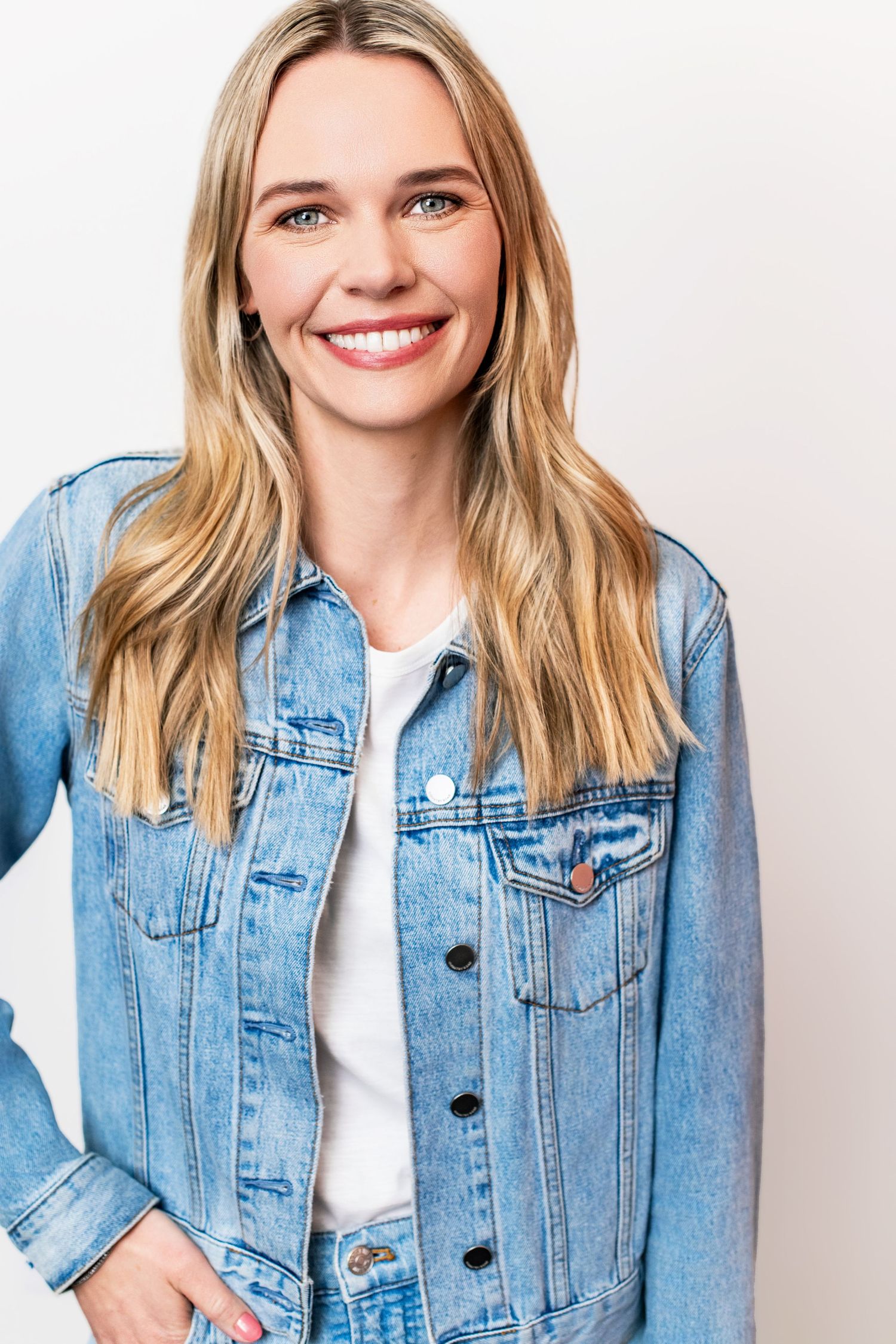 Female model wearing a denim jacket over a white t-shirt, photographed against a clean white backdrop for a modeling headshot in Los Angeles