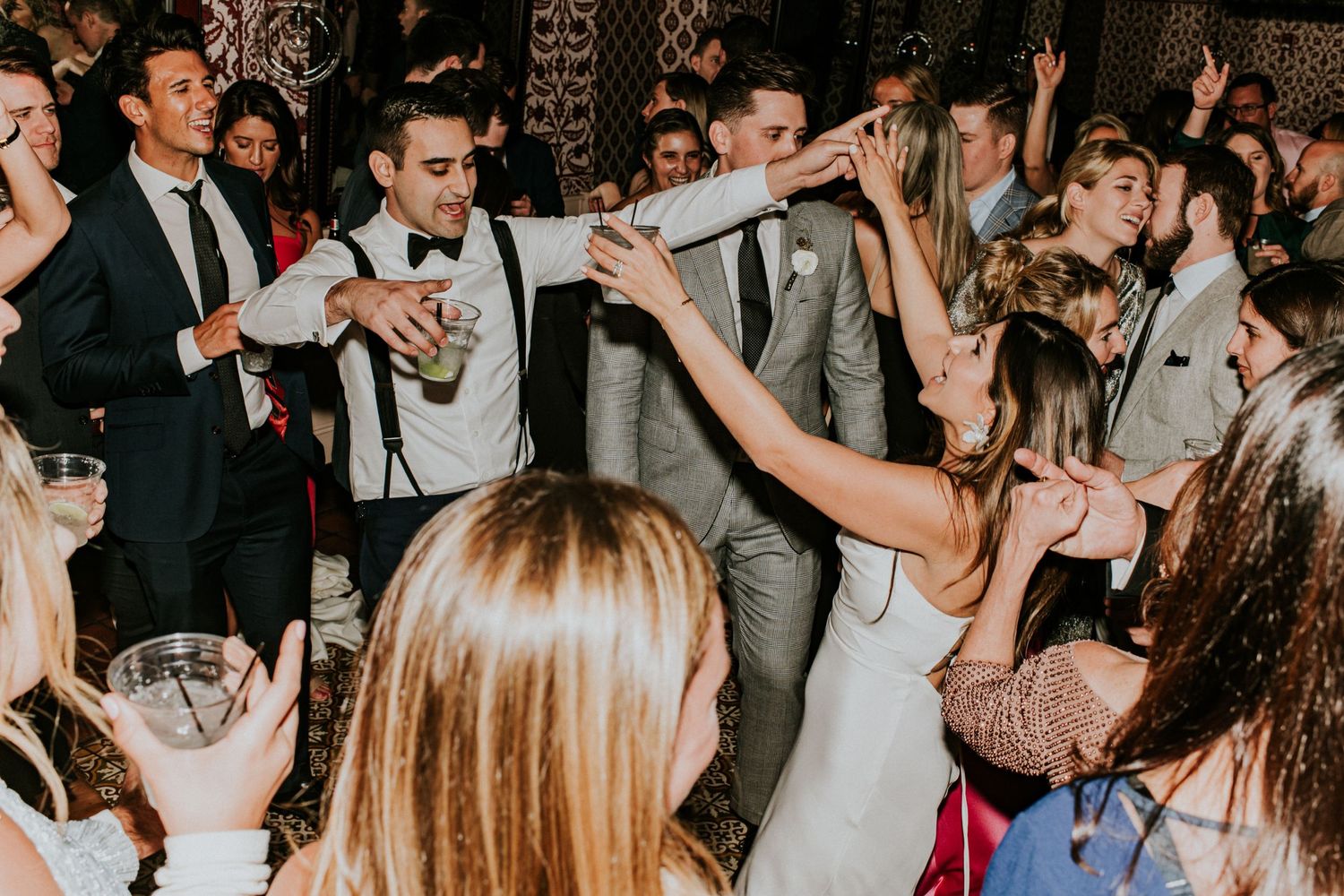 Bride and guests dancing and celebrating at a wedding reception, capturing the pure joy and energy of the moment.