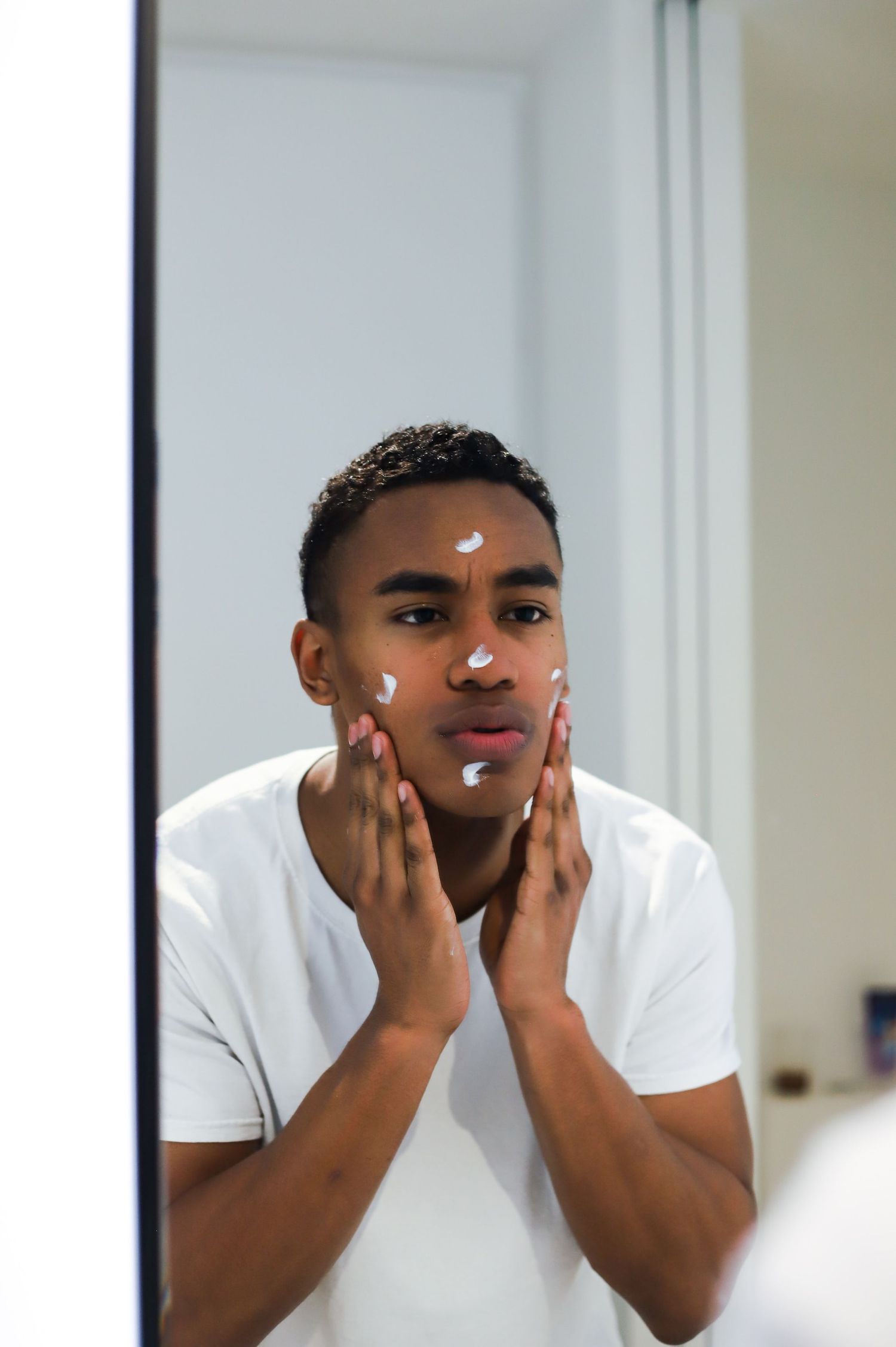 Actor applying skincare in the mirror, demonstrating simple self-care steps before a headshot session