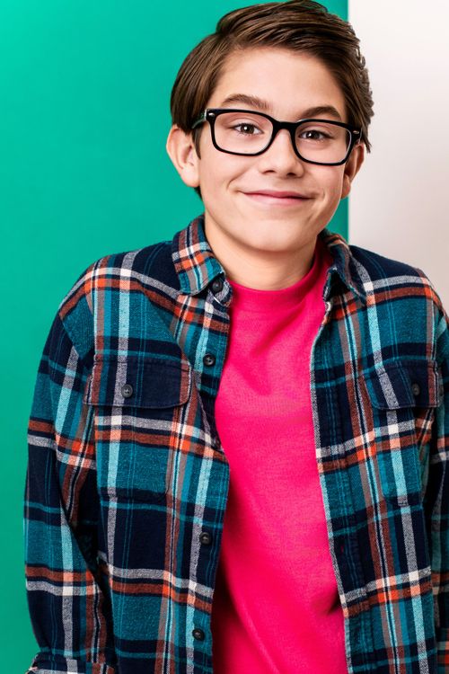 Smiling youth boy wearing glasses and a plaid shirt against a teal background for a professional commercial headshot.