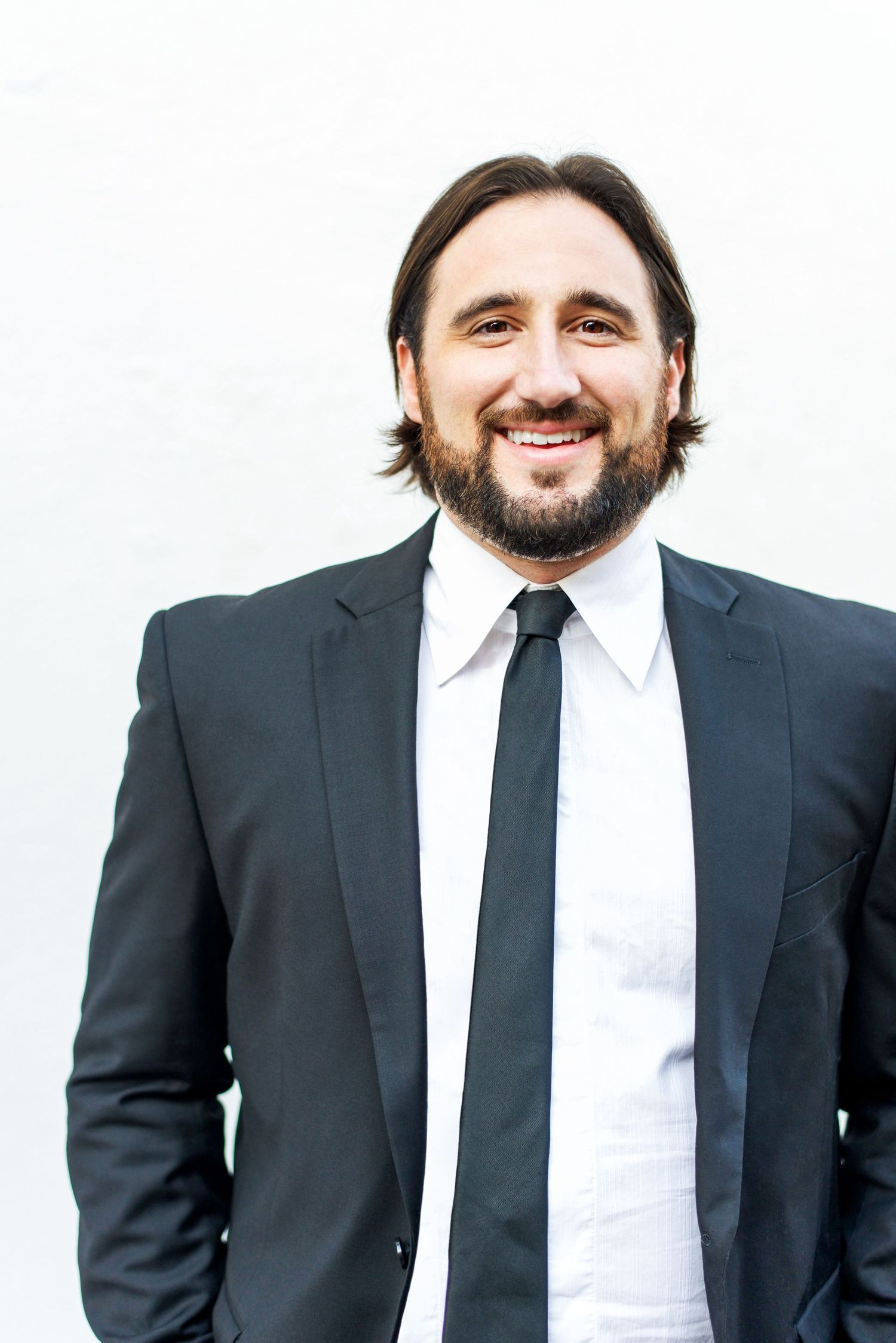 Male business professional wearing a black suit and tie, photographed against a white backdrop for a professional headshot in Los Angeles.