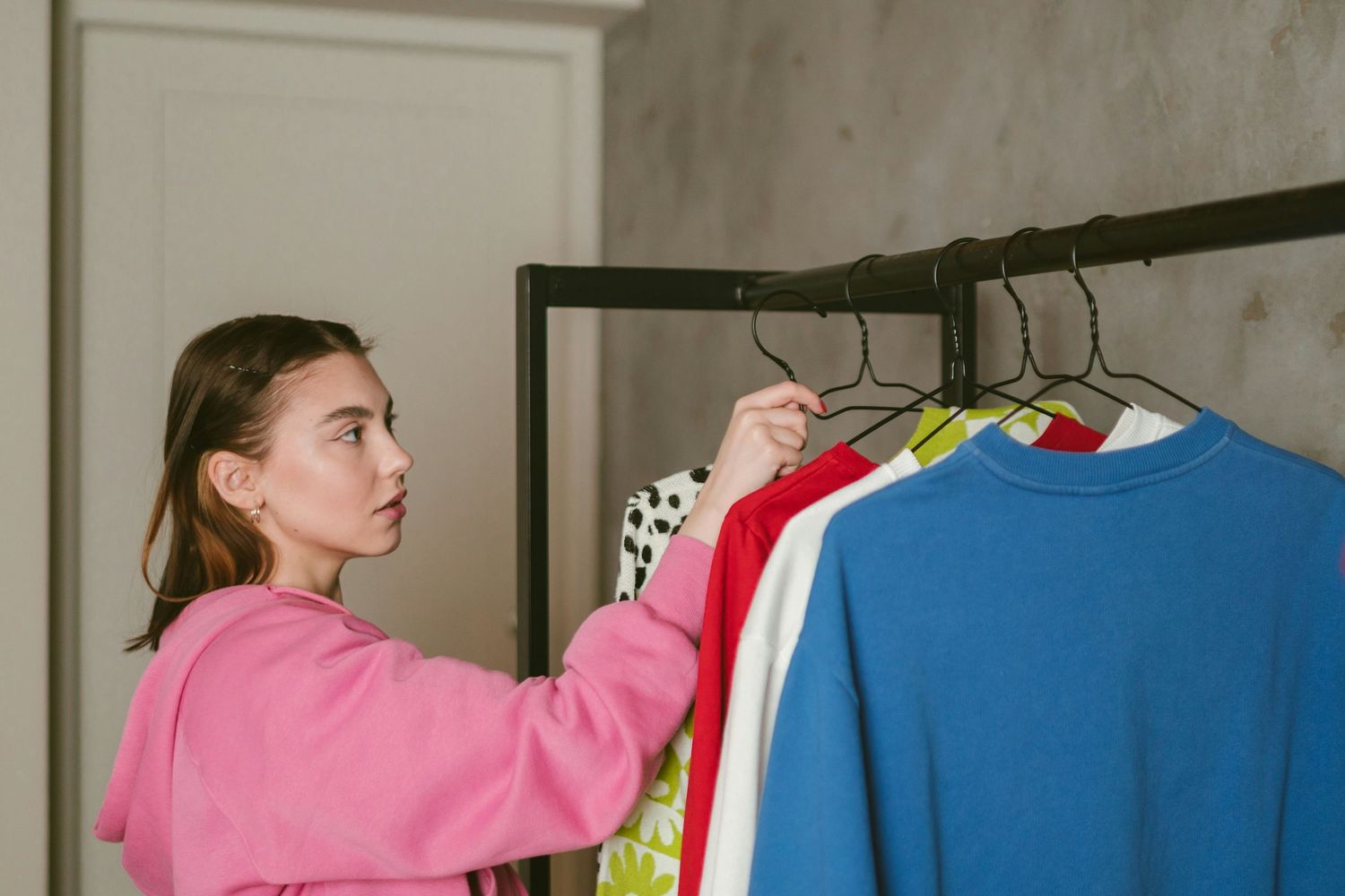 Student reviewing colorful wardrobe options on a clothing rack while preparing outfits for a headshot session.
