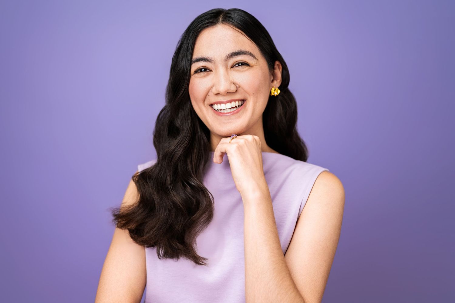 Professional woman smiling against a purple background photographed at a Los Angeles headshot studio.