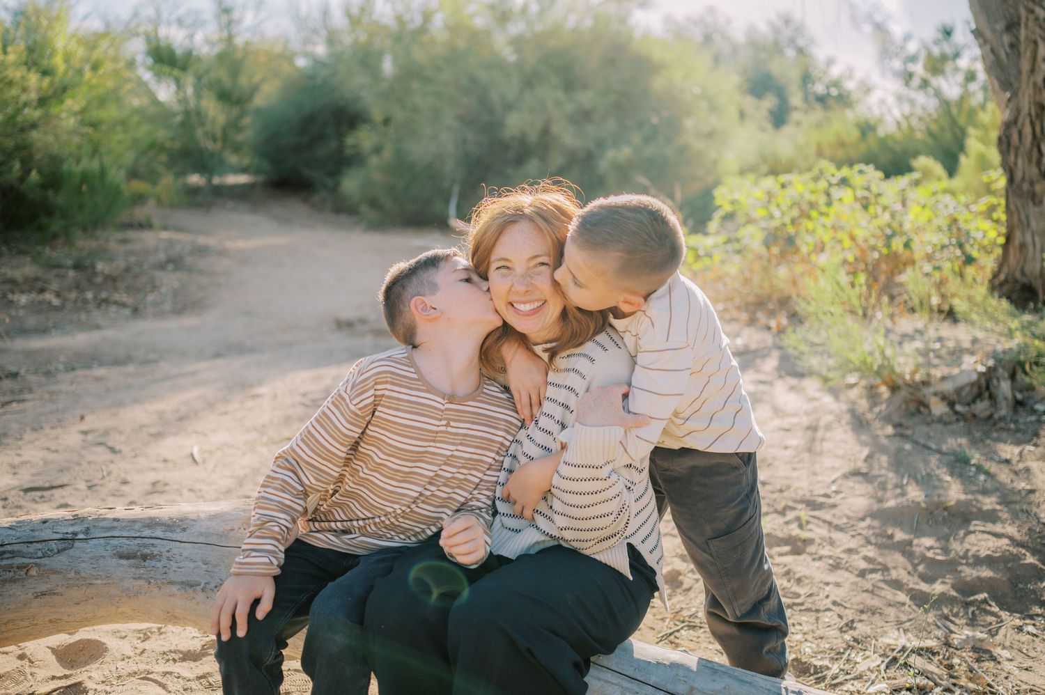 A loving family shares tender moments together on a desert hiking trail during a warm afternoon. Phoenix Arizona family photographer.