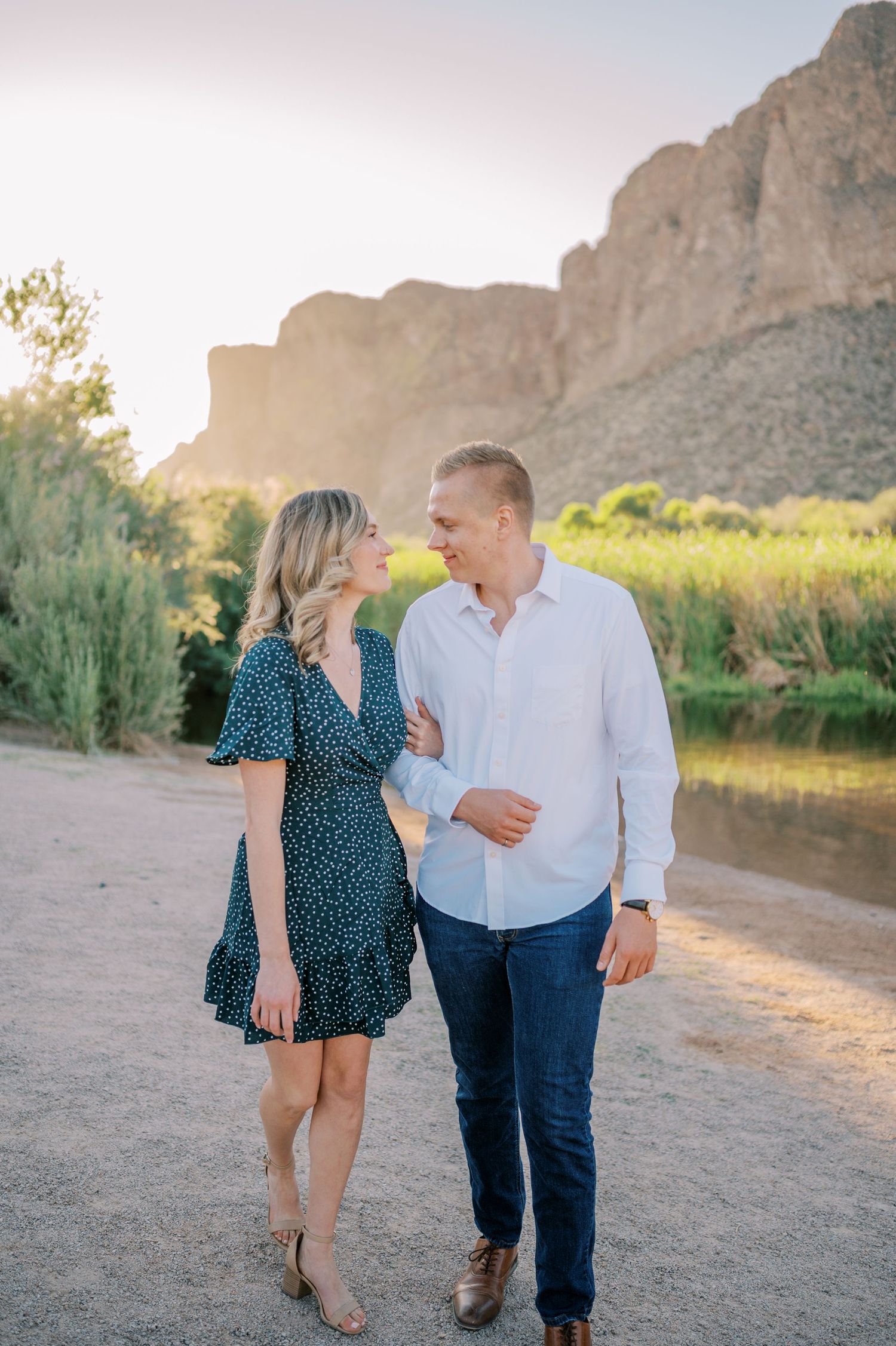 A couple shares a romantic moment against a backdrop of towering desert cliffs during golden hour. Phoenix Arizona couples photographer.