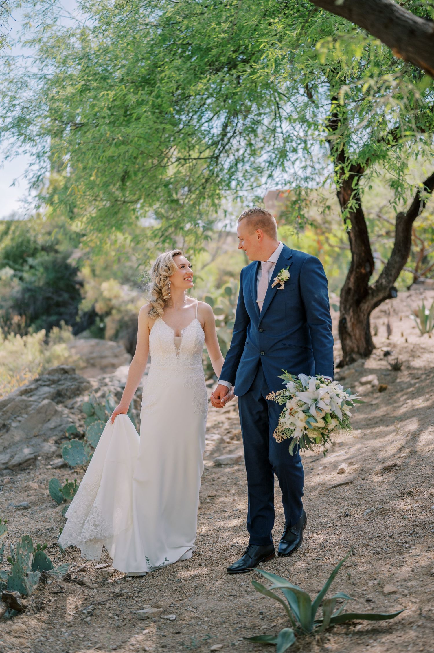 A couple in wedding attire shares intimate moments surrounded by green trees and natural scenery. Phoenix Arizona couples photographer.