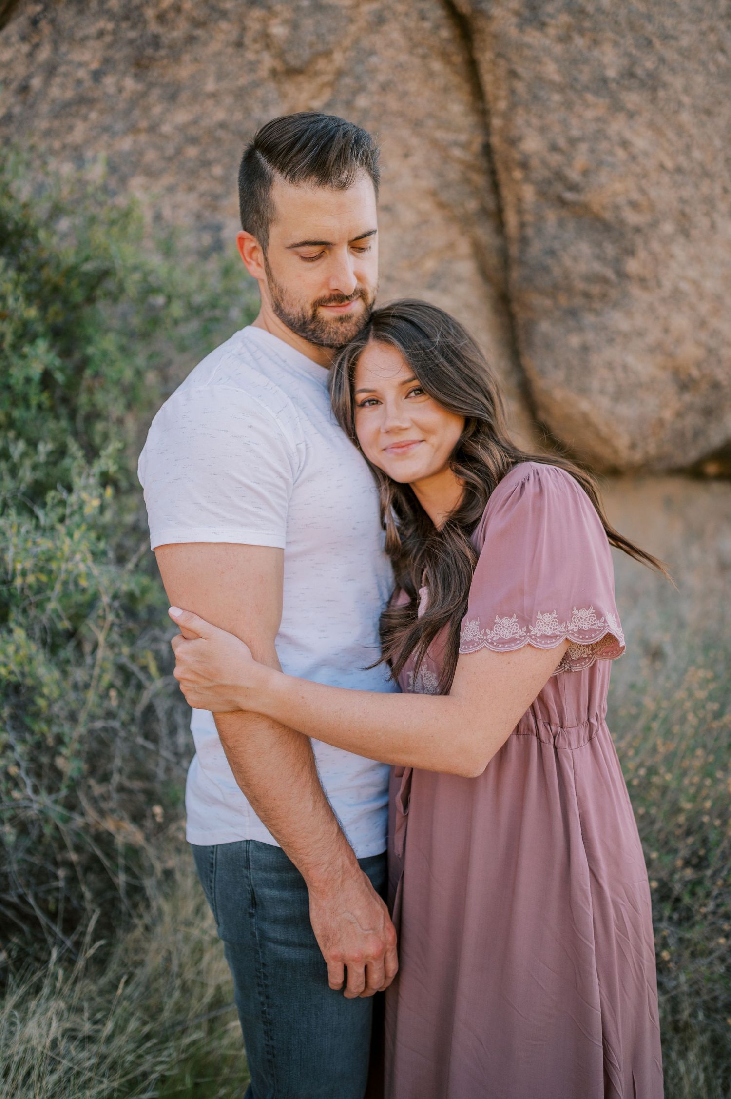 A couple shares tender moments together against a rocky desert backdrop. Phoenix Arizona couples photographer.