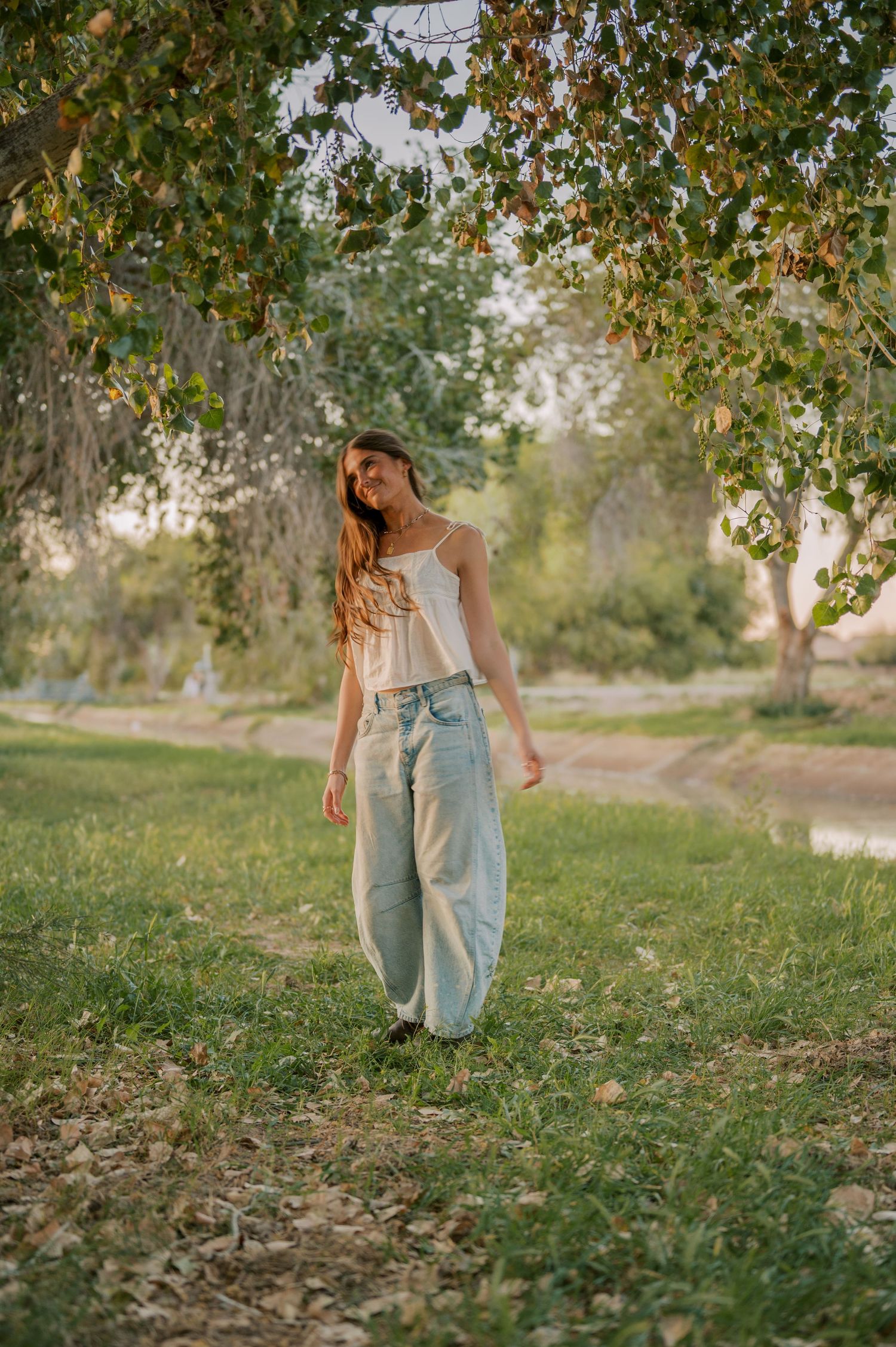 Elegant senior photos in a shaded green tunnel of trees by water in Gilbert Arizona