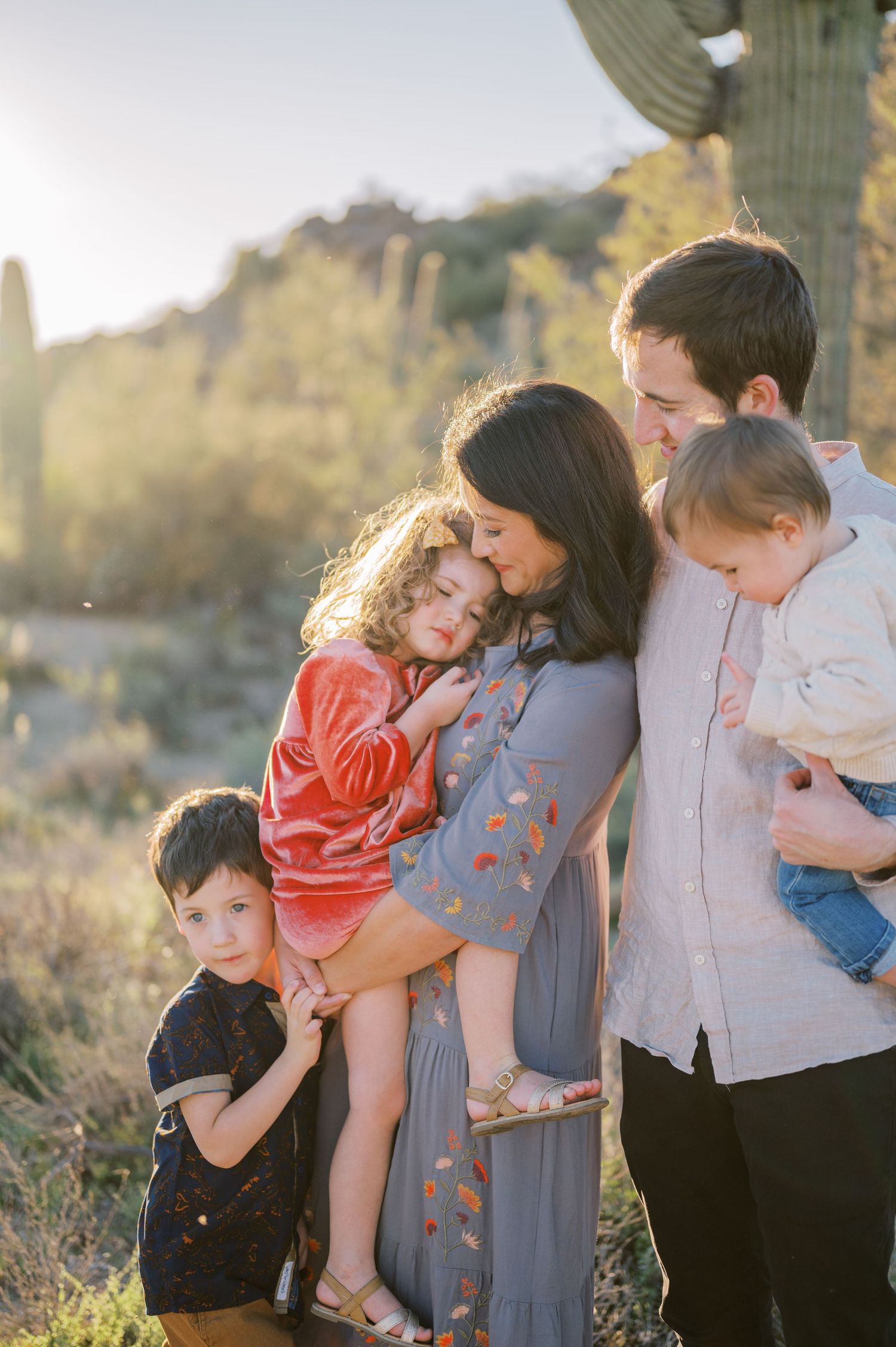 A loving family shares tender moments together in a sunlit outdoor setting during a photo session. Phoenix Arizona family photographer.