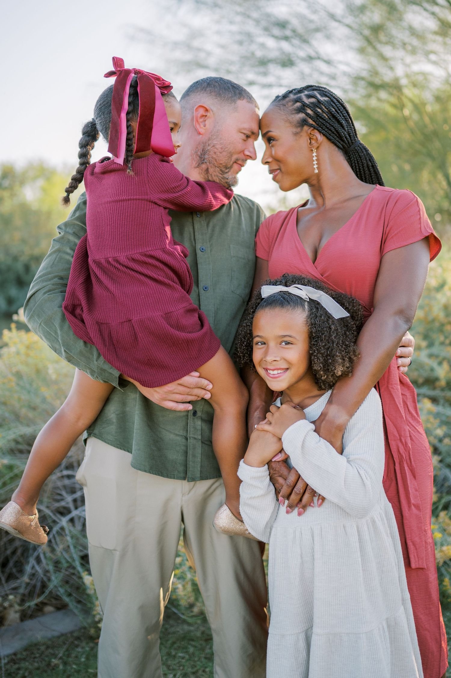A loving family shares tender moments together outdoors in coordinated burgundy and neutral outfits. Phoenix Arizona family photographer.
