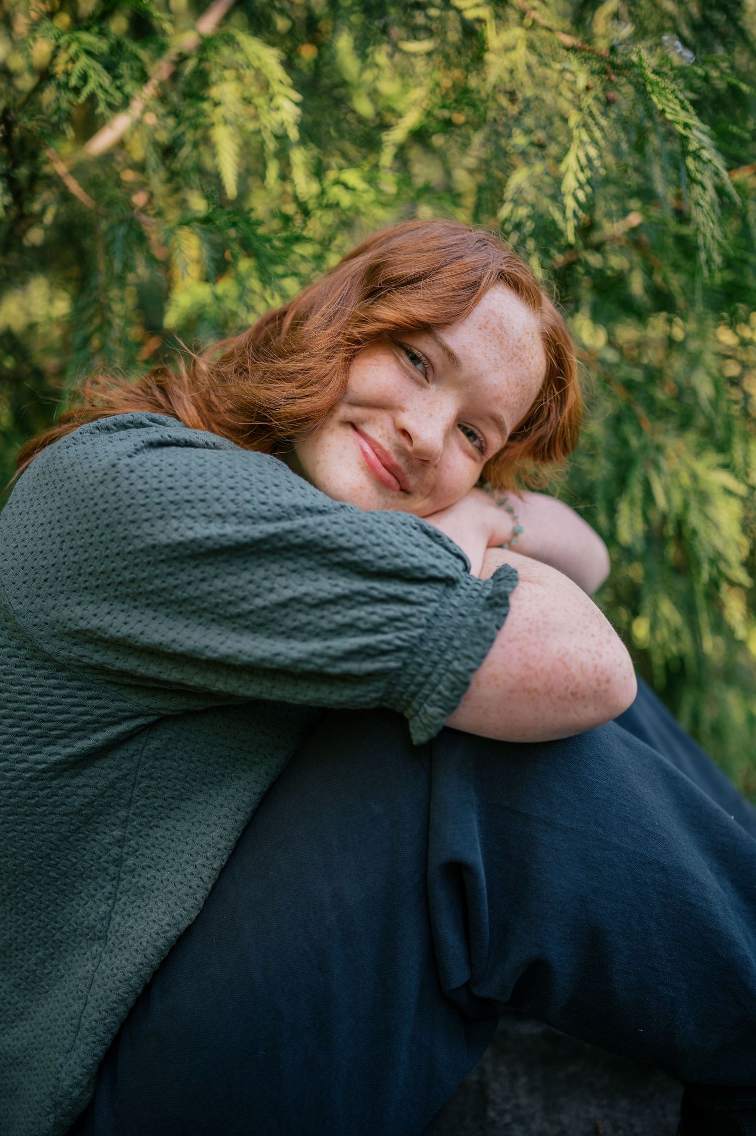 Person in green sweater embraces someone in dark clothing against leafy green background. Phoenix Arizona senior photographer.