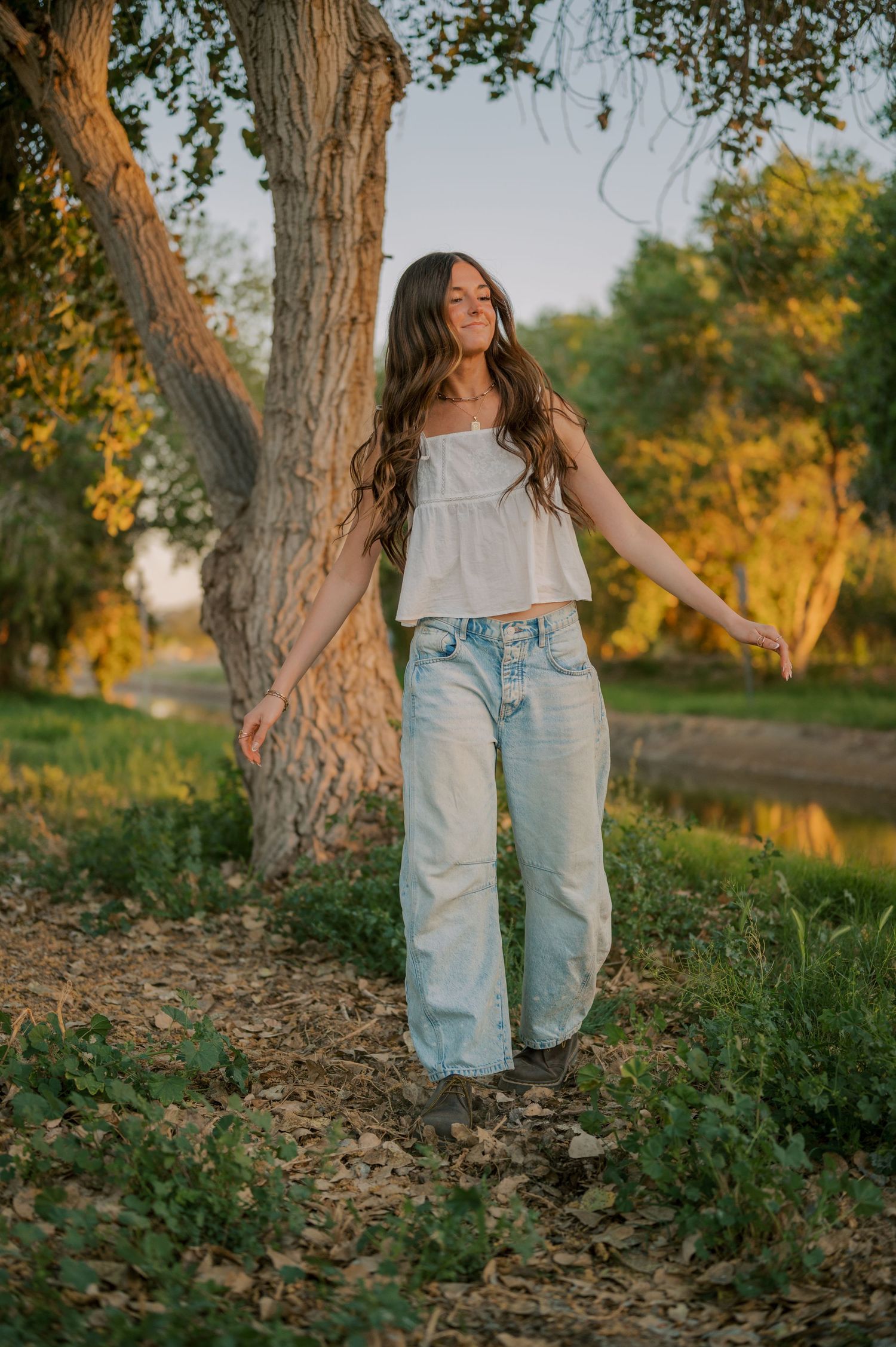 High school senior portrait in a tree-lined canal with soft, whimsical light