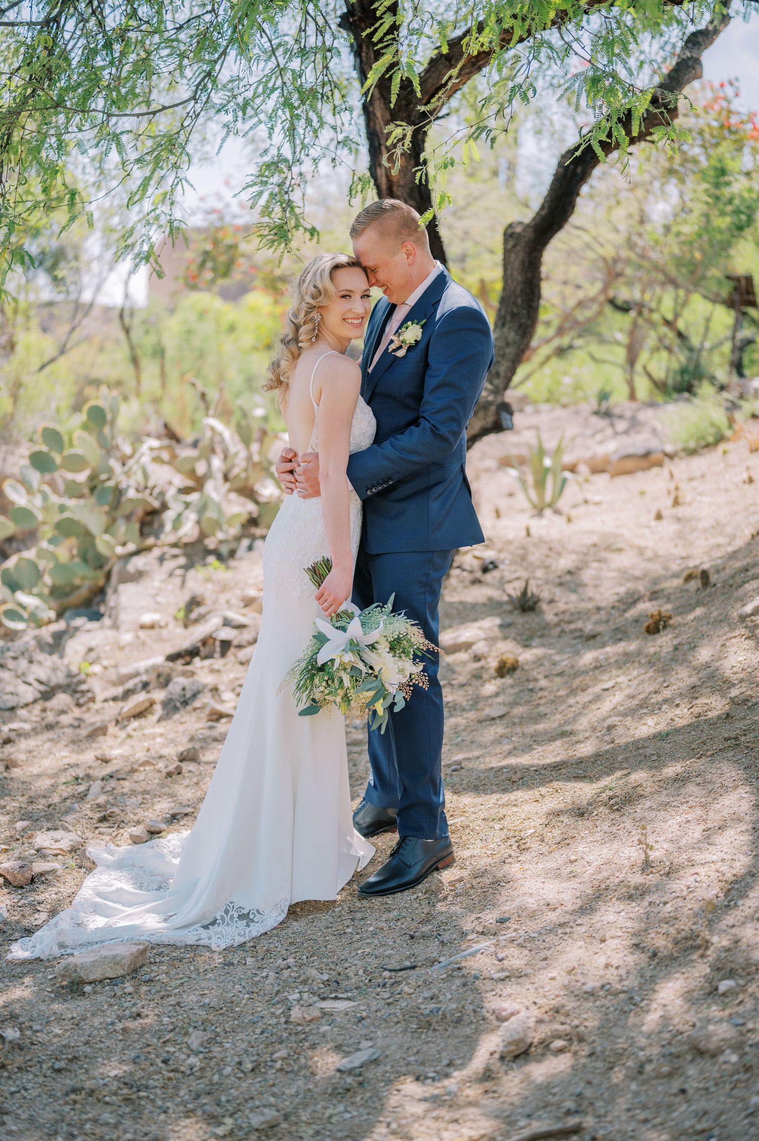A couple shares a romantic moment in a desert landscape setting during their wedding photoshoot. Phoenix Arizona couples photographer.