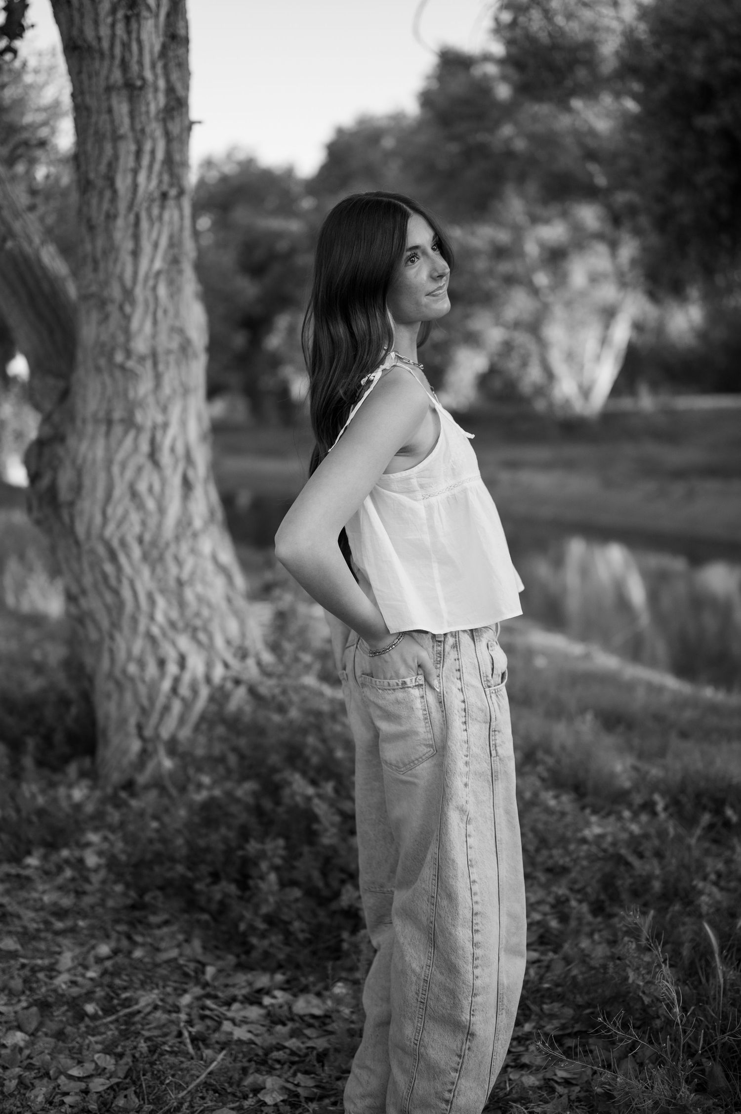 Senior girl standing by canal with tree canopy creating a natural frame