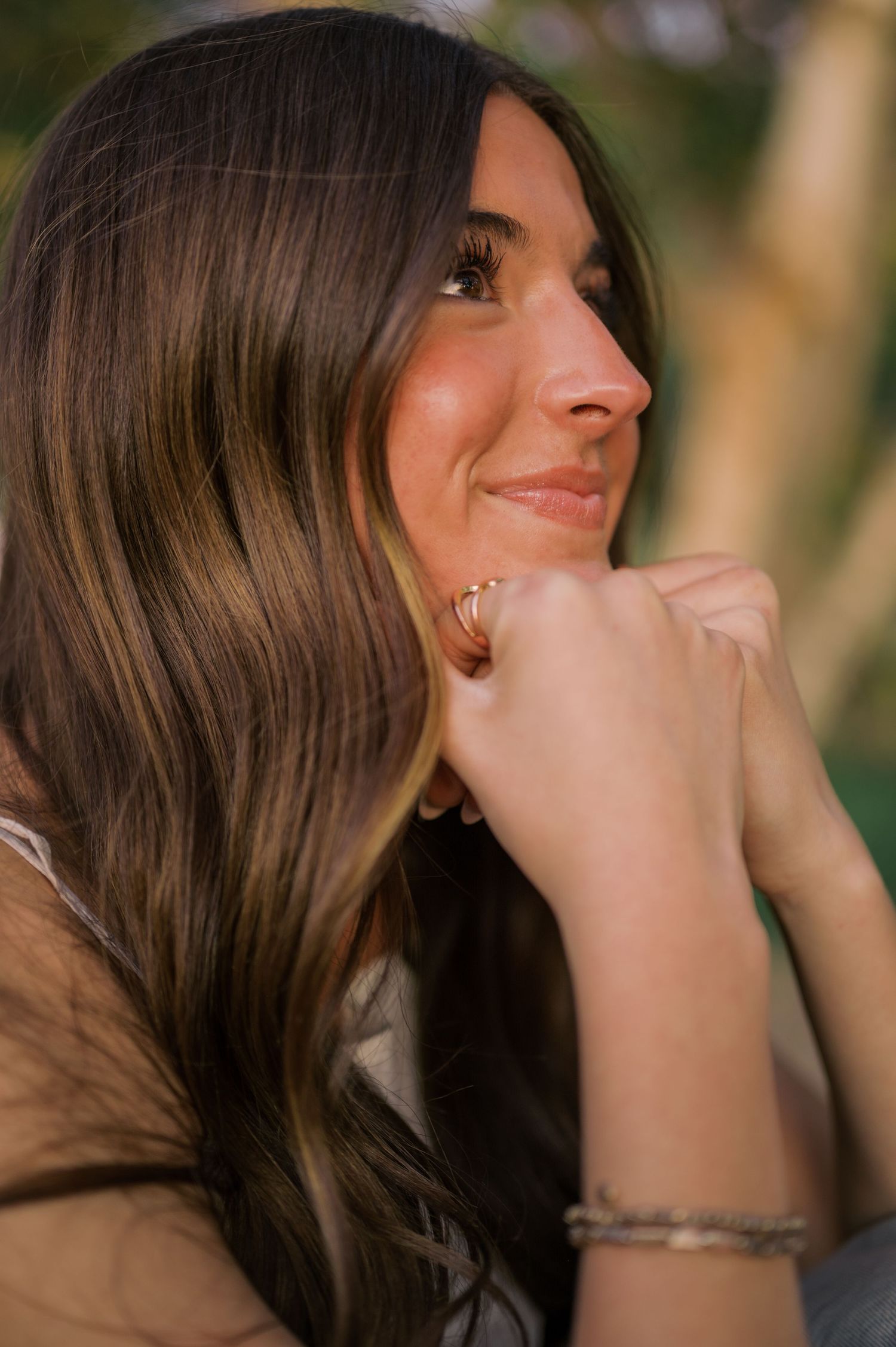 Close-up senior portrait with soft natural light and blurred greenery background