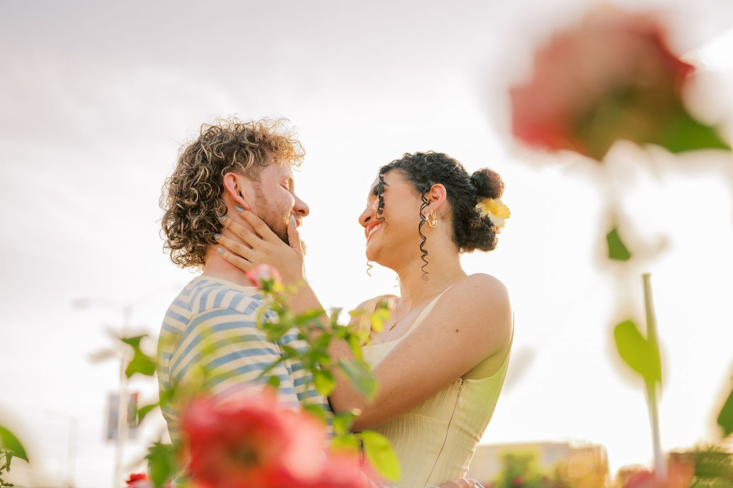 A joyful couple sharing a romantic moment outdoors, surrounded by blooming roses in warm golden light.