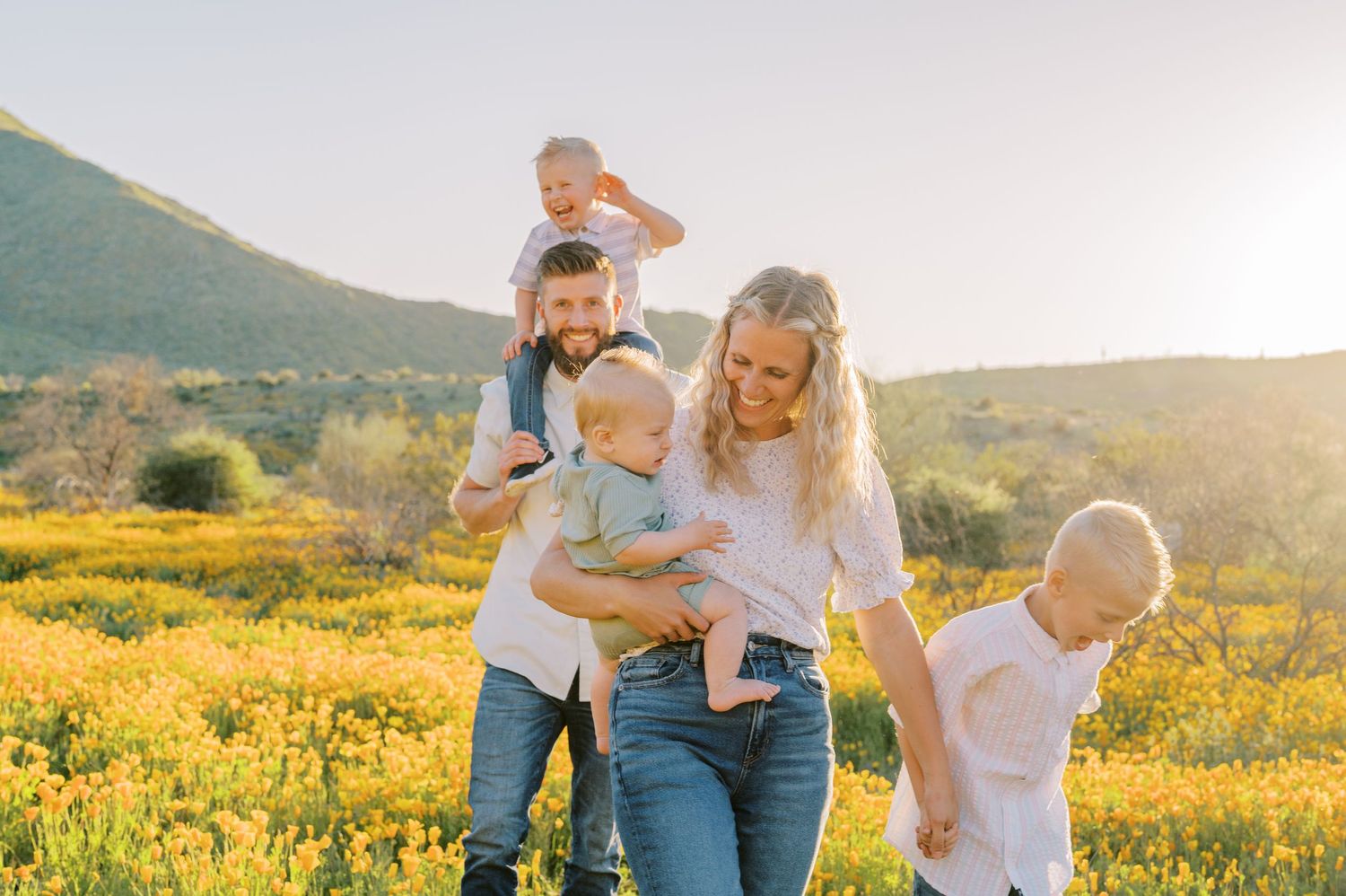 Family enjoying a sunset photoshoot together in a field of yellow wildflowers during golden hour. Phoenix Arizona family photographer.