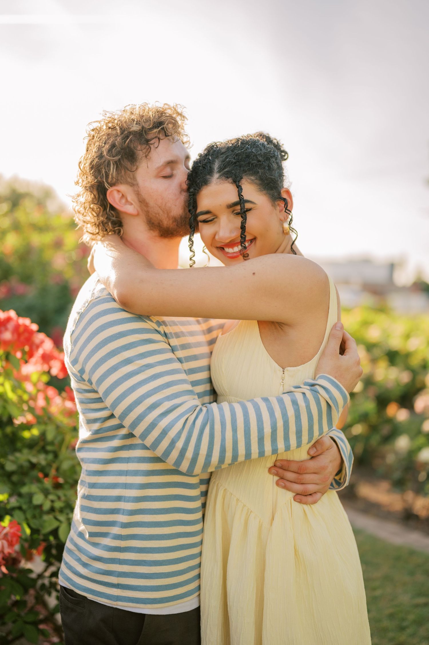 Couple embracing in rose garden during romantic sunset session