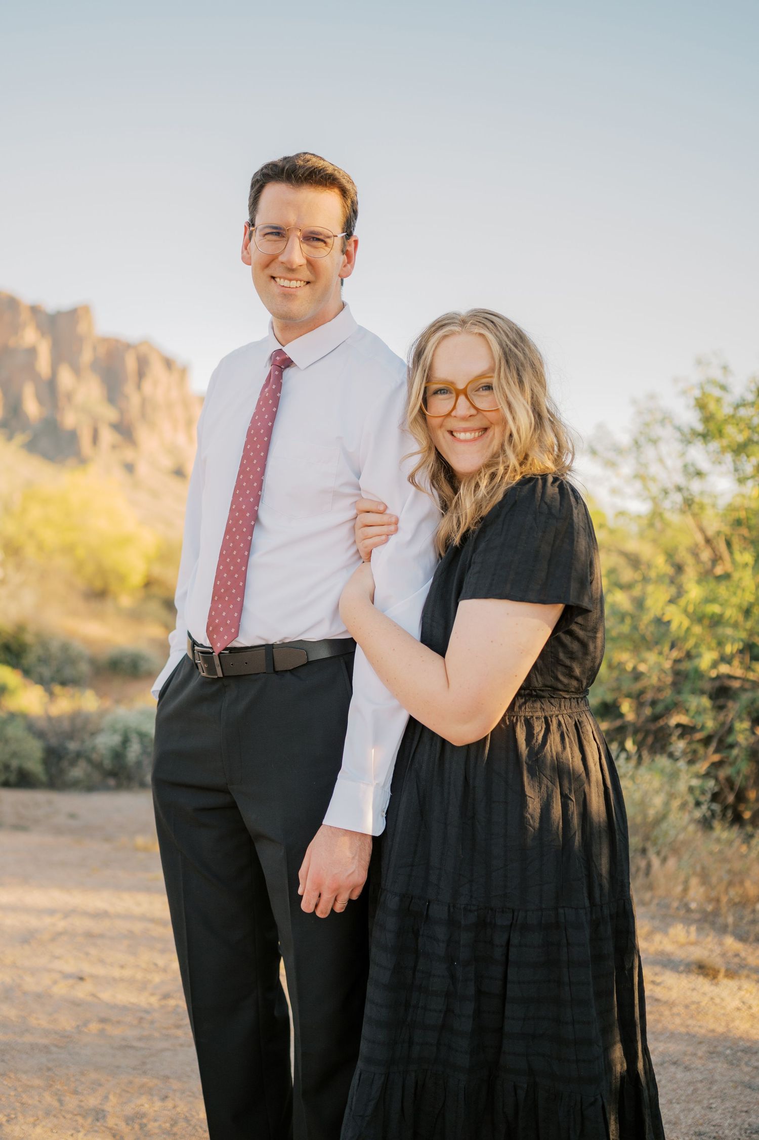 A smiling couple poses outdoors in the Arizona desert