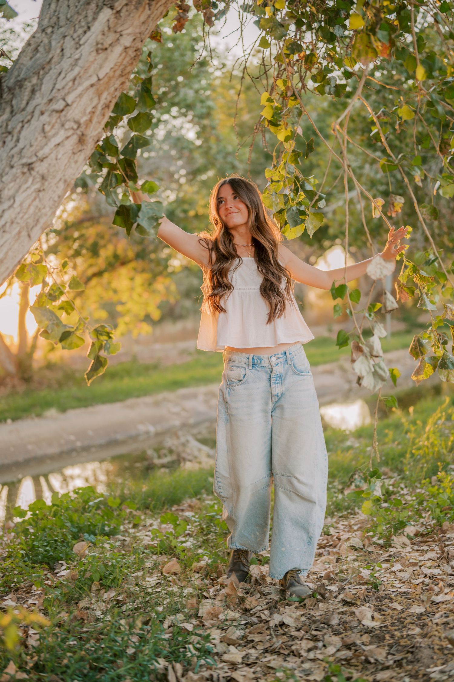 Senior portrait with flowing dress in a tree-lined canal in Gilbert Arizona