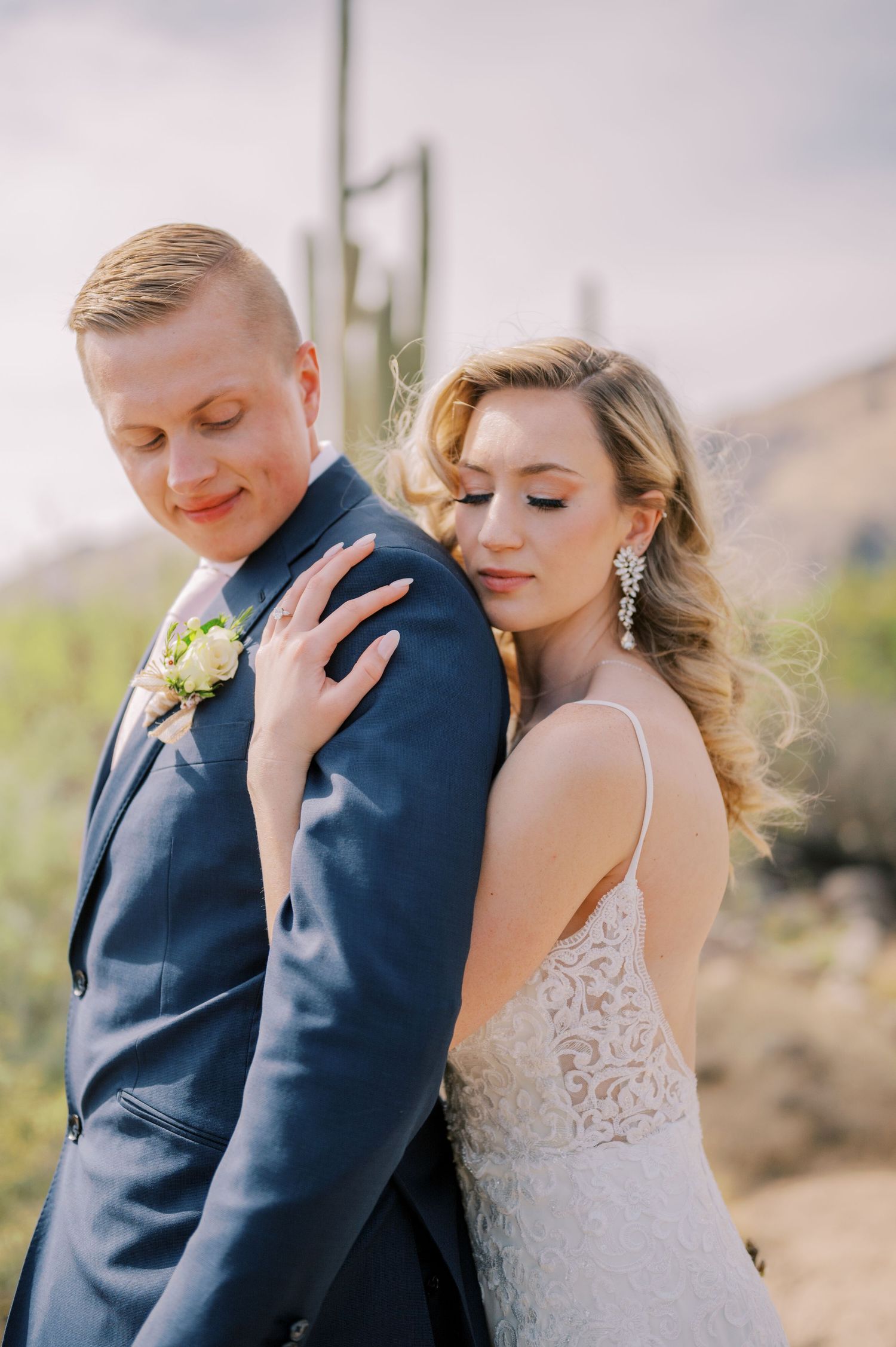 A couple in wedding attire share intimate moments in a desert landscape with mountains in the background. Phoenix Arizona photographer