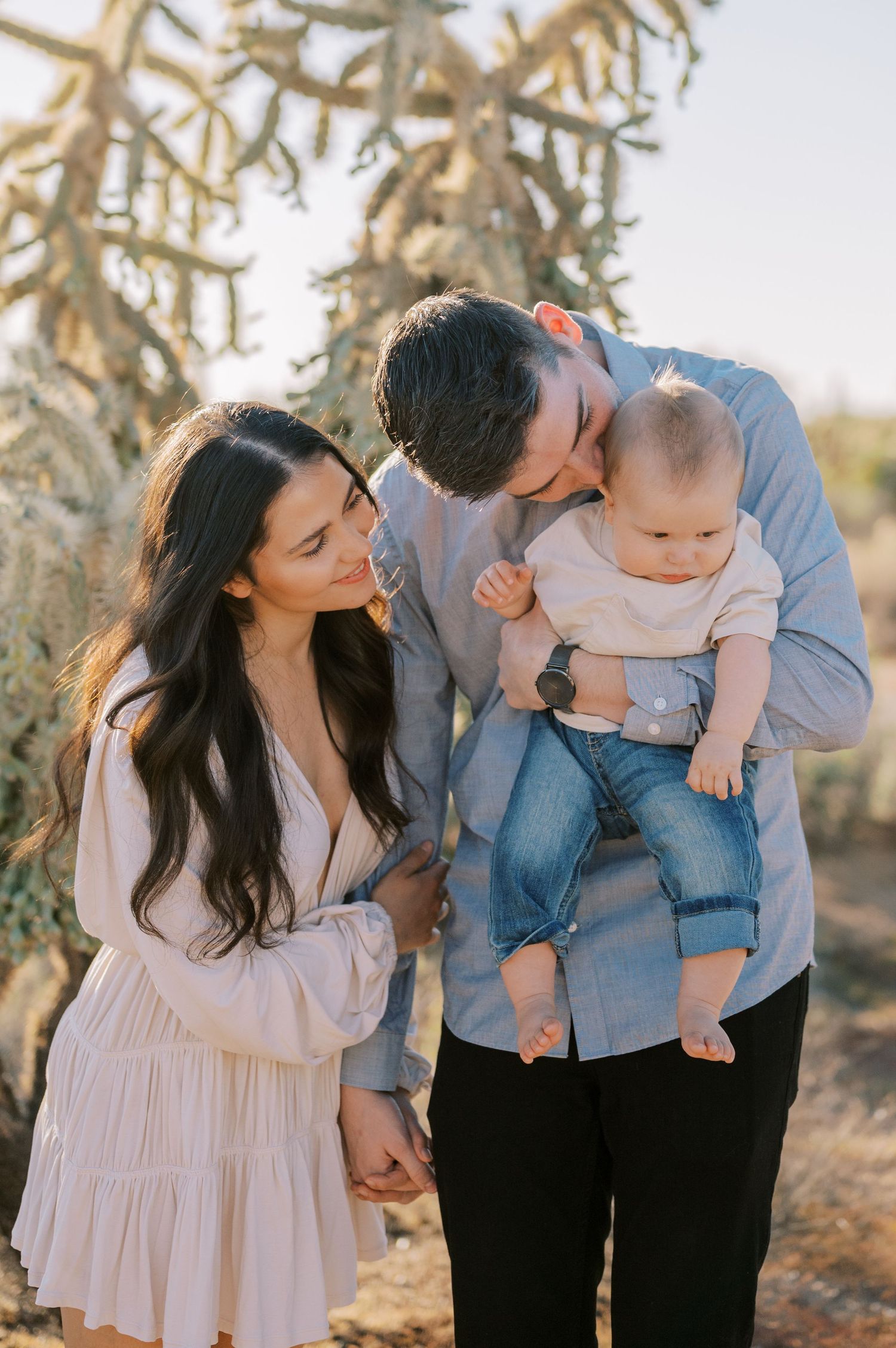 Family of three poses together outdoors during golden hour for portrait session. Phoenix Arizona family photographer.