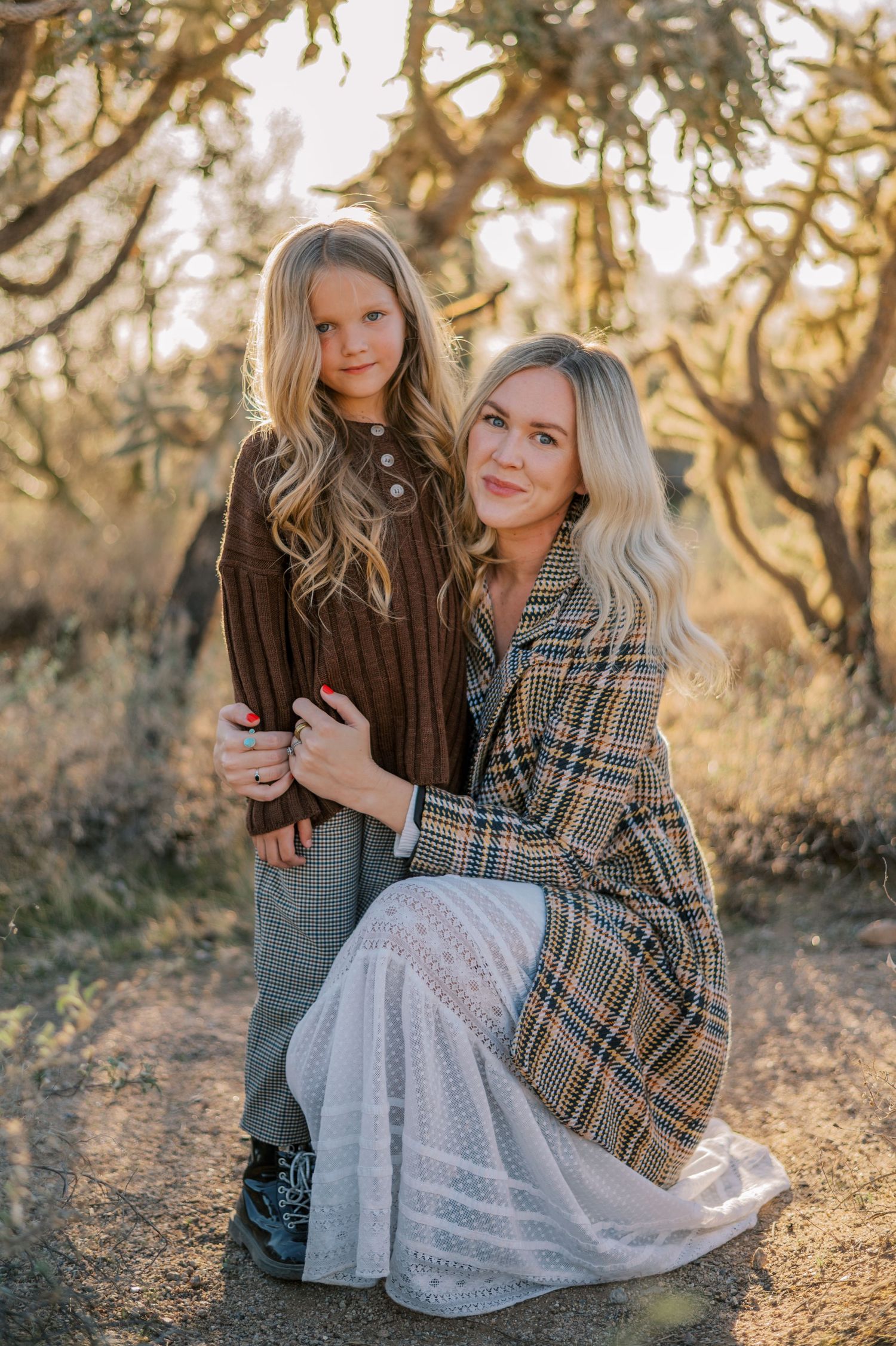 Two friends in autumn outfits pose together outdoors at sunset in a dreamy woodland setting. Phoenix Arizona family photographer.