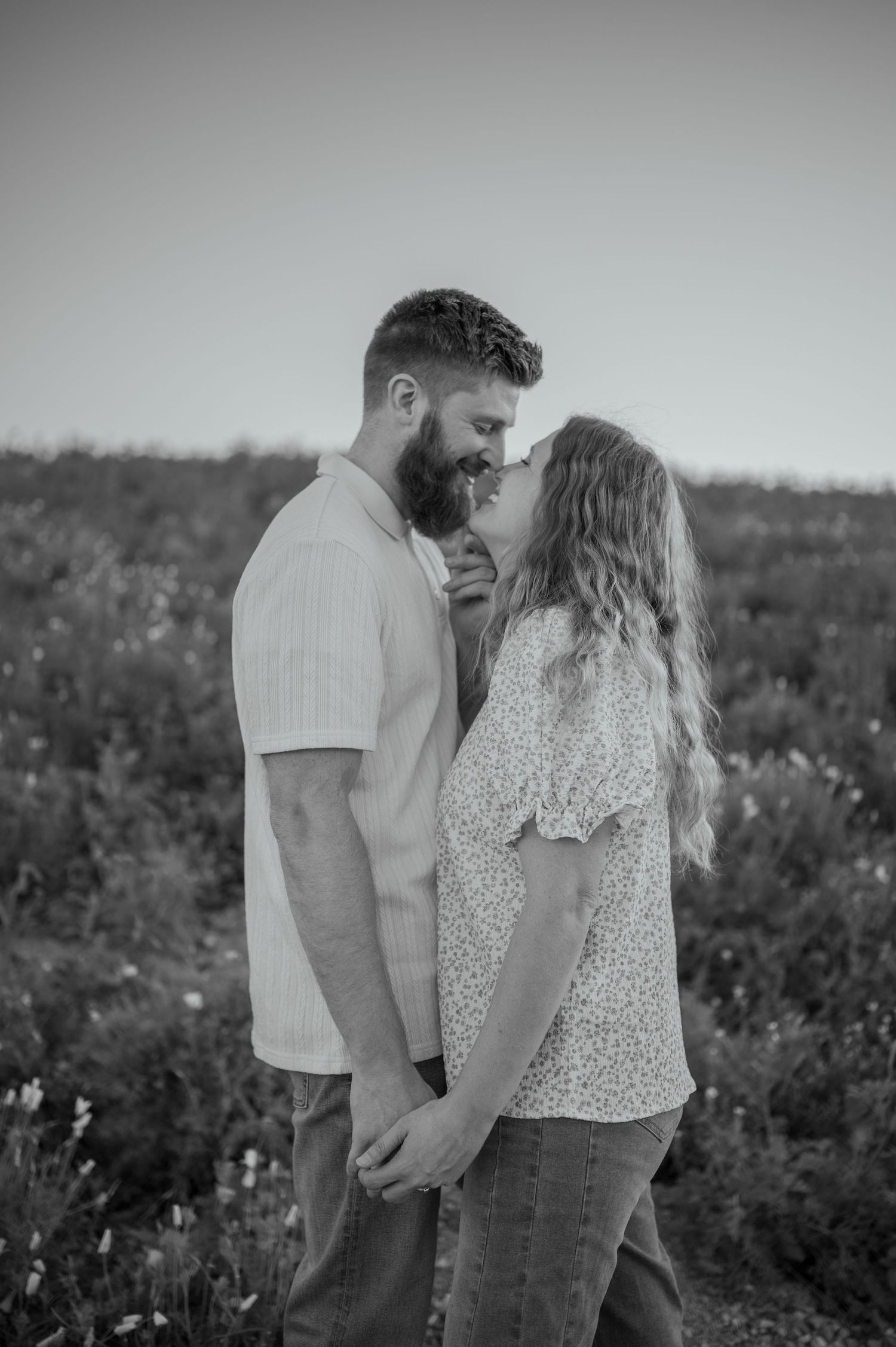A romantic black and white portrait of a couple sharing an intimate moment in a wildflower field. Phoenix Arizona couples photographer.