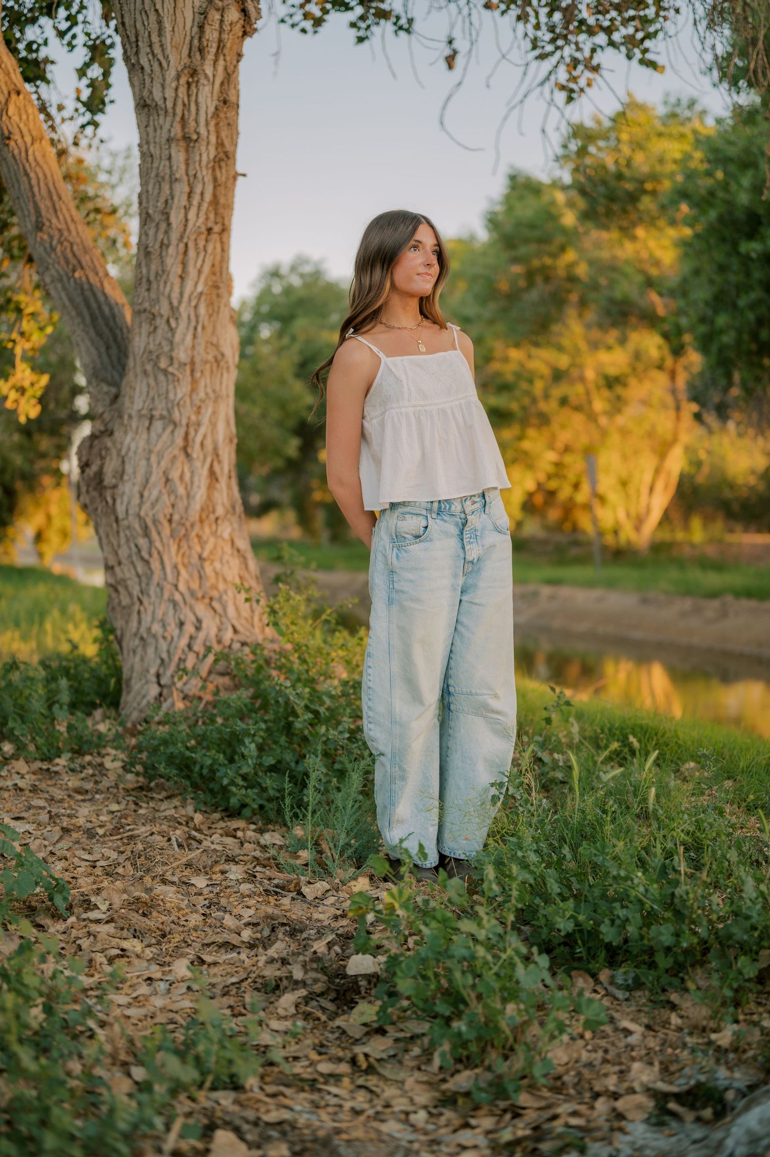 Senior girl standing by canal with tree canopy creating a natural frame