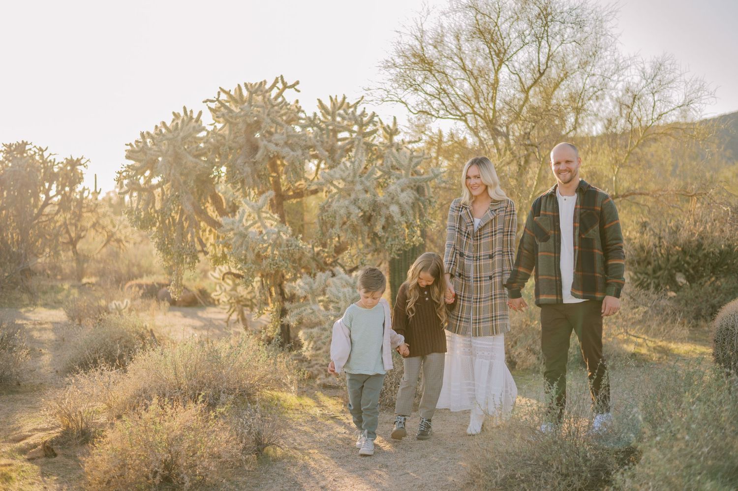 Family poses together in golden desert landscape during sunset photoshoot in Arizona. Phoenix Arizona family photographer.