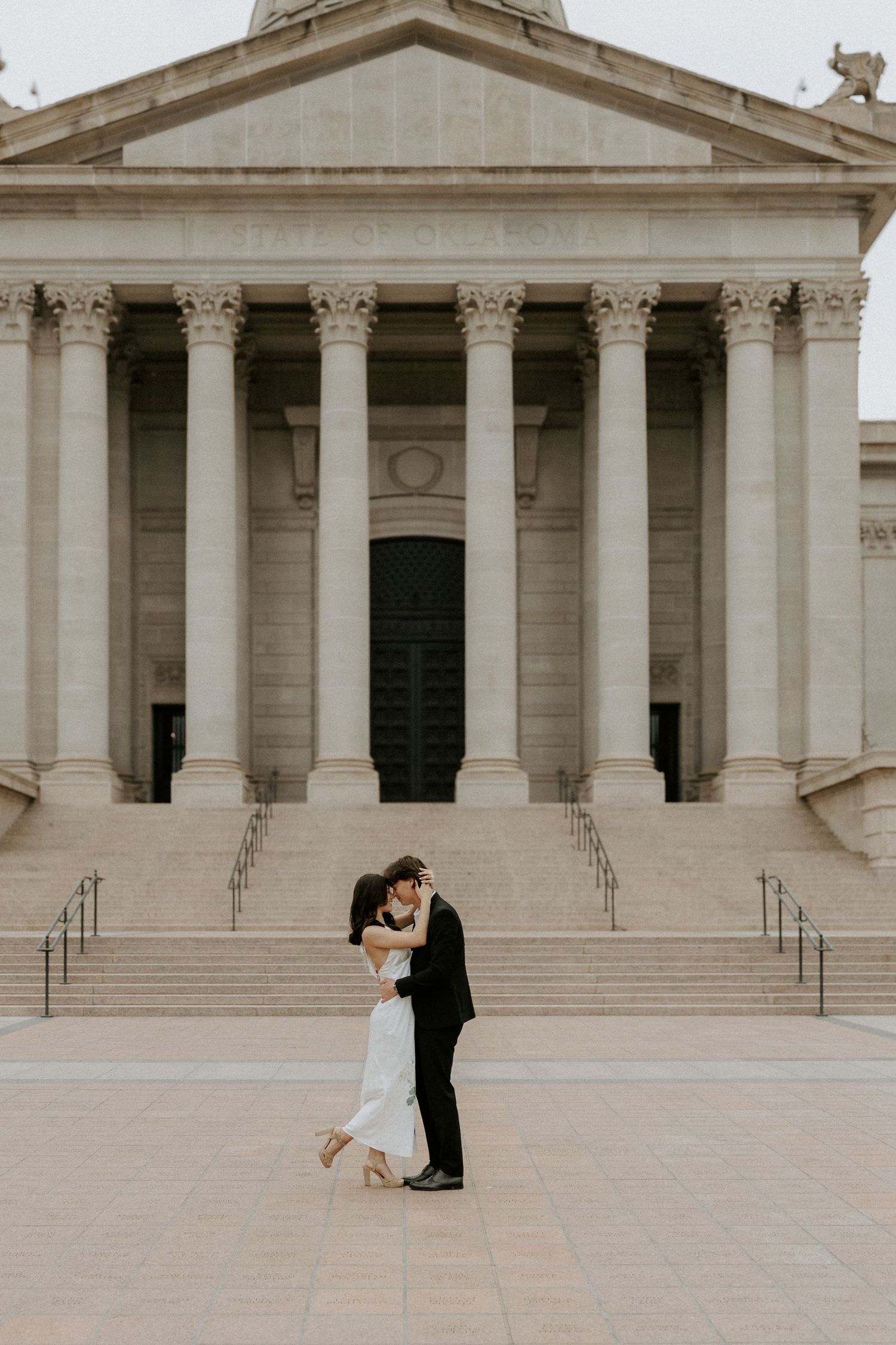 Minimalist architectural photo of a couple dancing in front of a neoclassical building with columns.