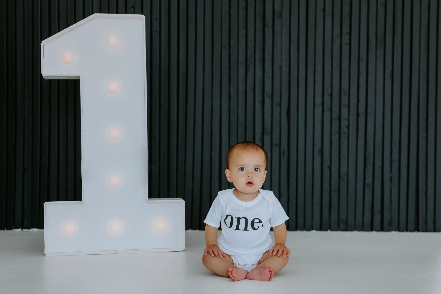 Minimalist baby photo shoot with polka dot backdrop and soft lighting.