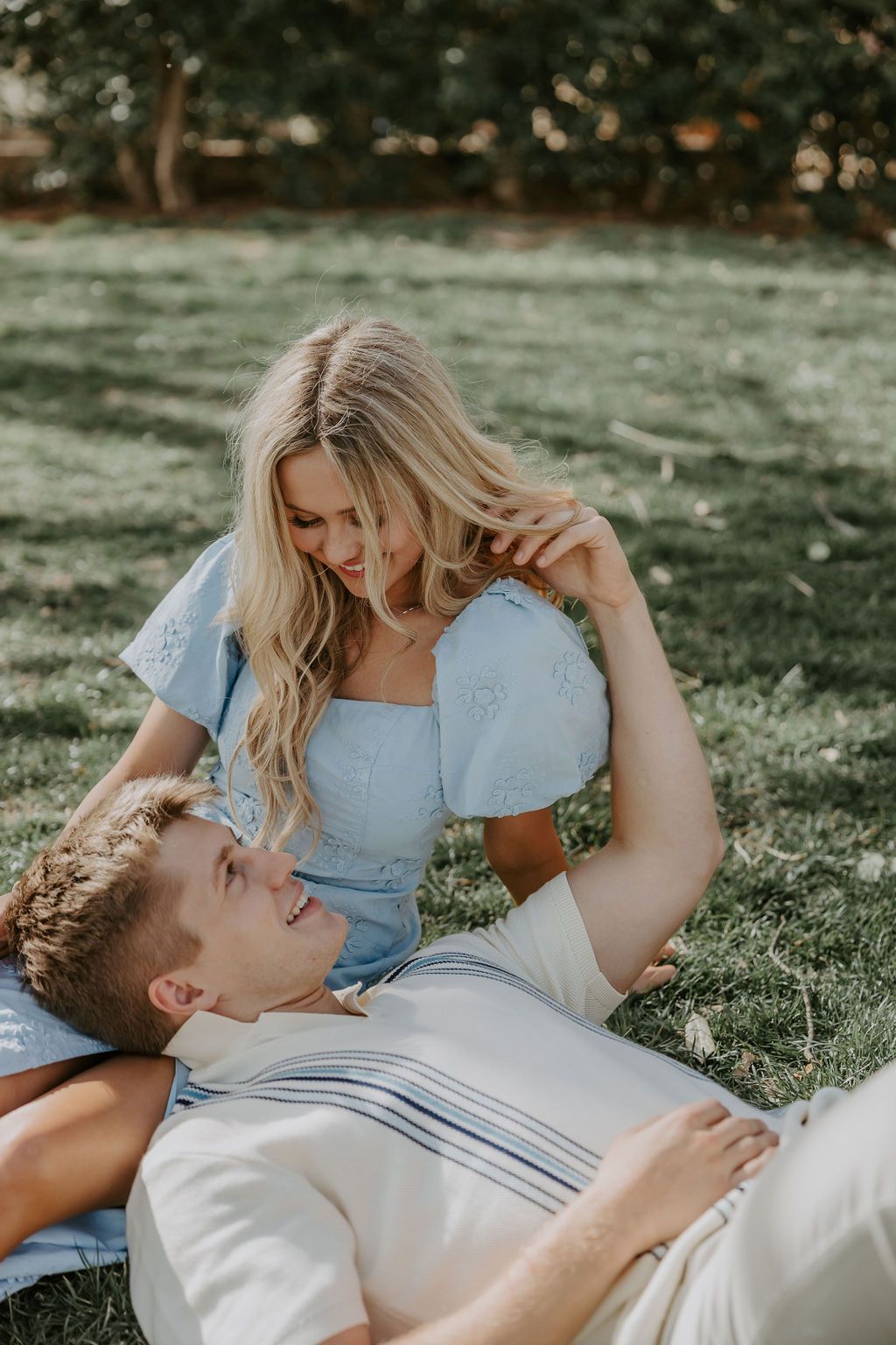 Couple relaxing together on grass during outdoor photo session.