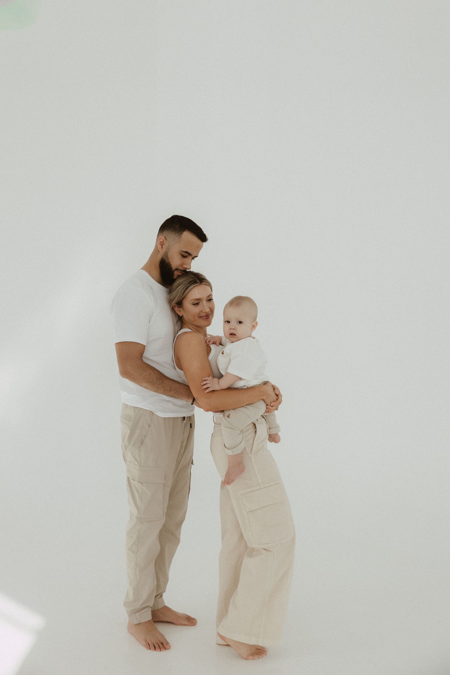 Minimalist family portrait in light neutral colors showing tender interaction.