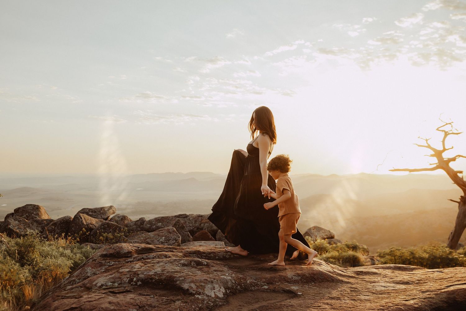 Silhouettes embracing on mountain overlook during golden hour.