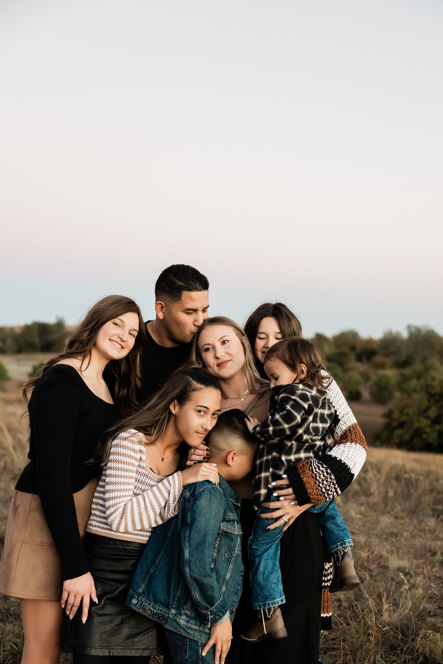 Intimate family gathering captured during sunset in a natural outdoor setting.