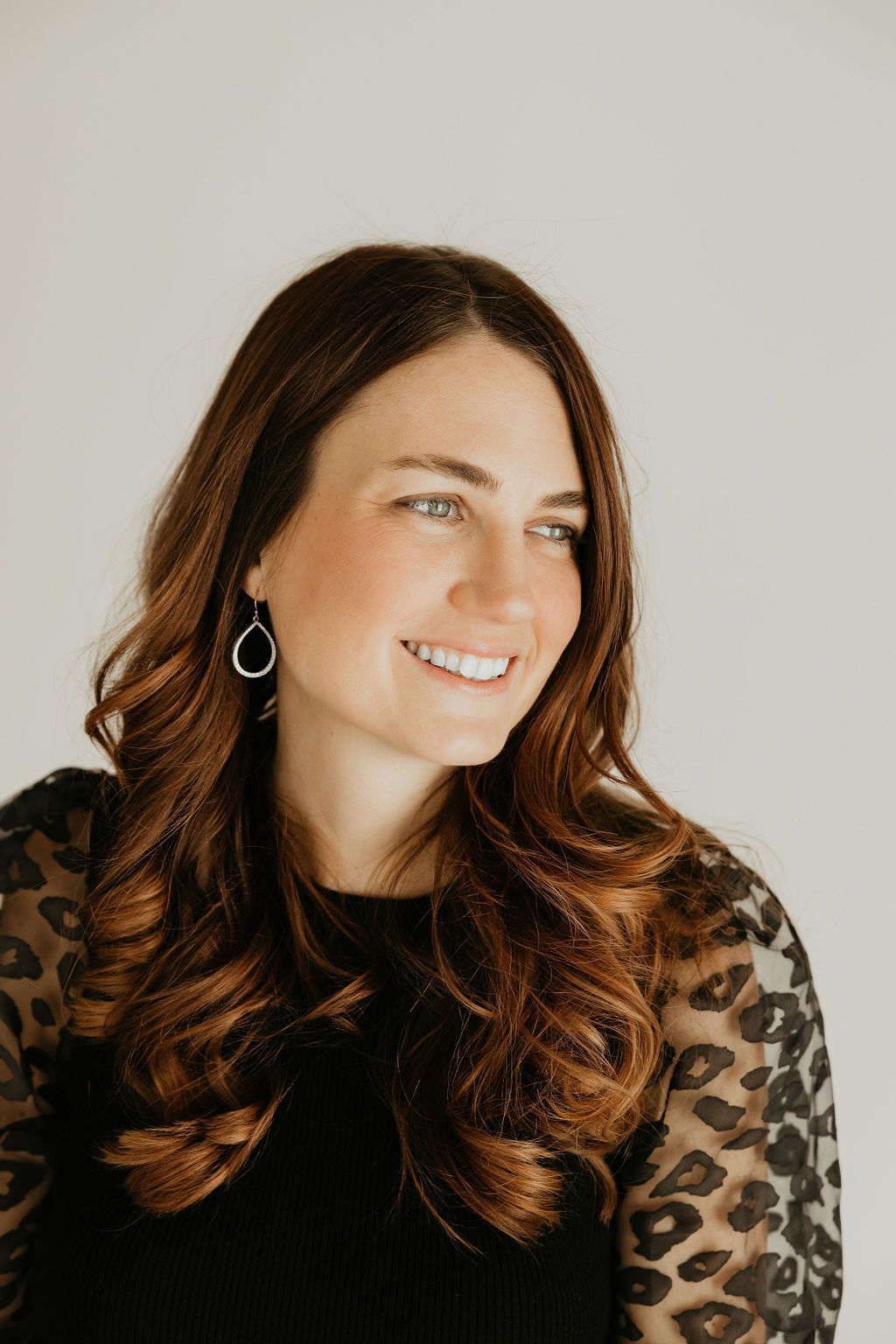 Stylish portrait session featuring leopard print top against minimalist background.