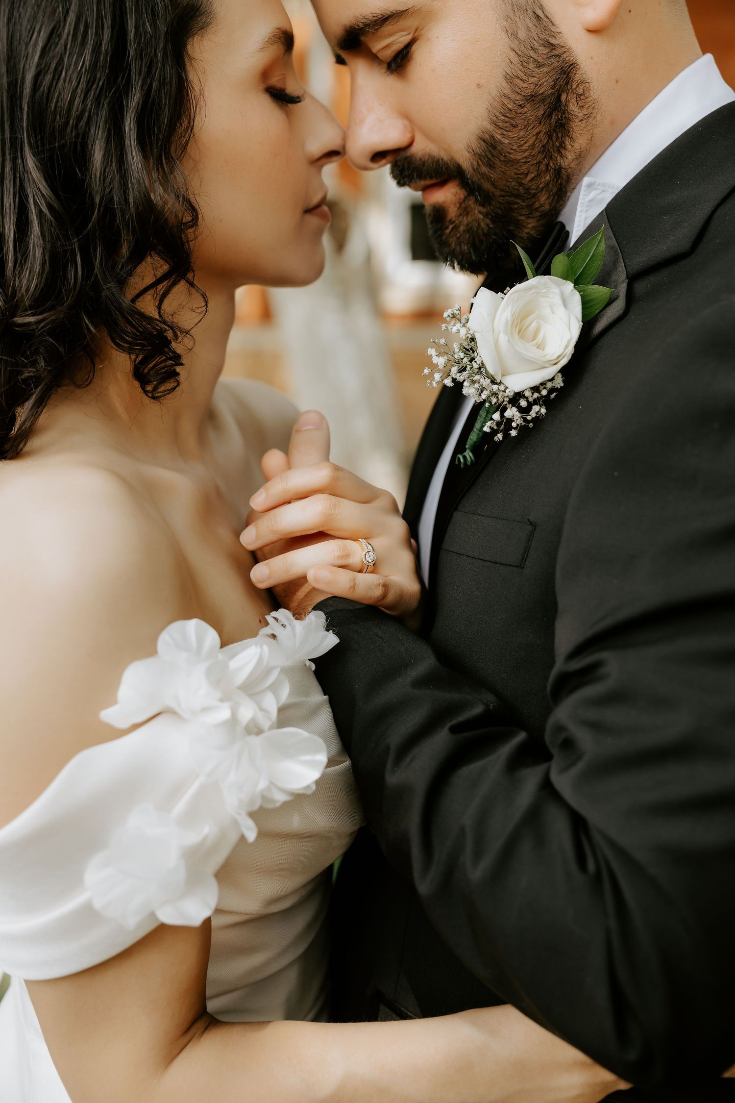 Intimate close-up wedding portrait with white floral boutonniere detail.