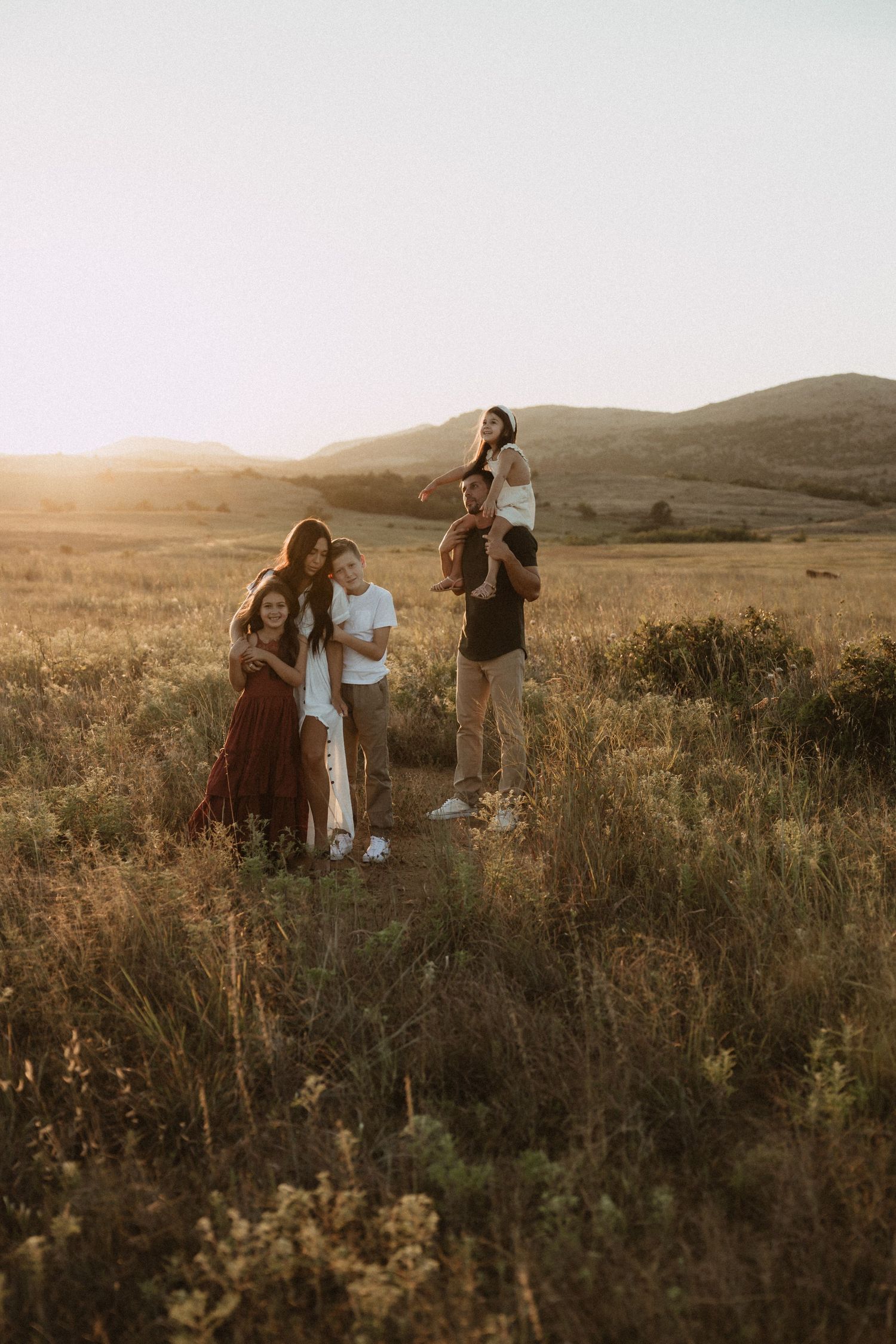 Group gathered in a scenic meadow during golden hour with mountains in background.