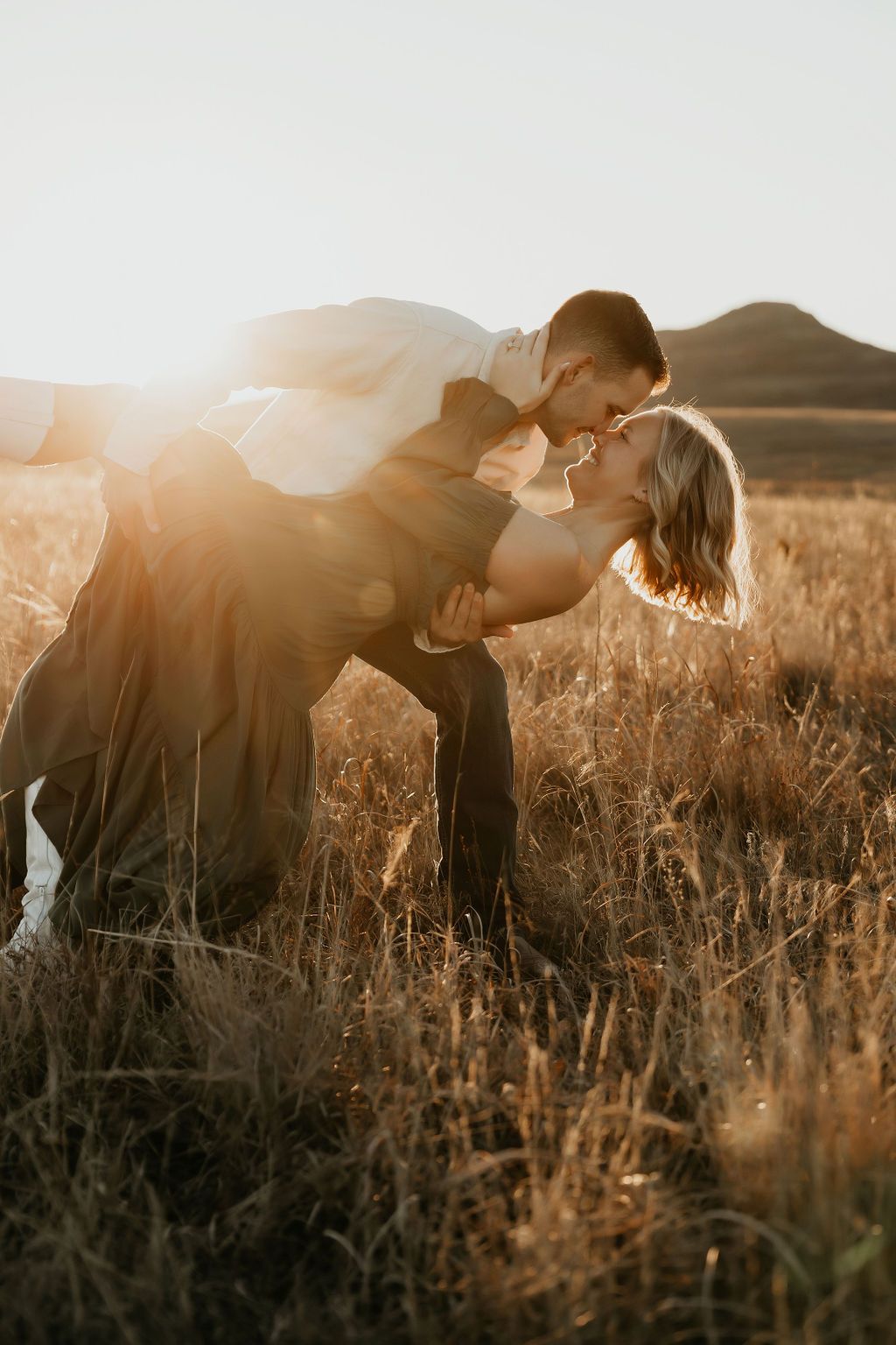 A romantic dip pose in a sun-drenched field at sunset.