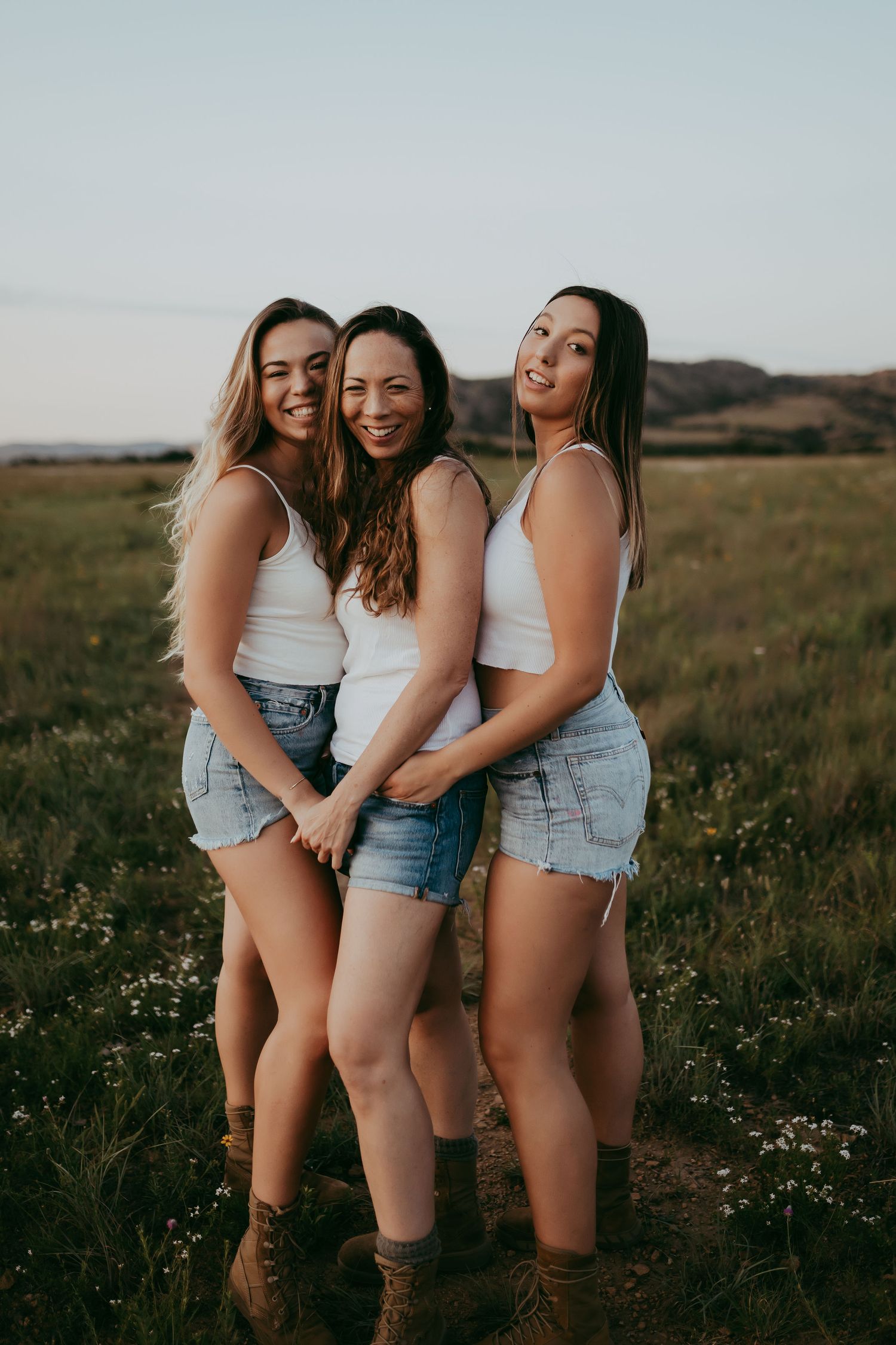 Friends in denim shorts share laughter in a summer field.